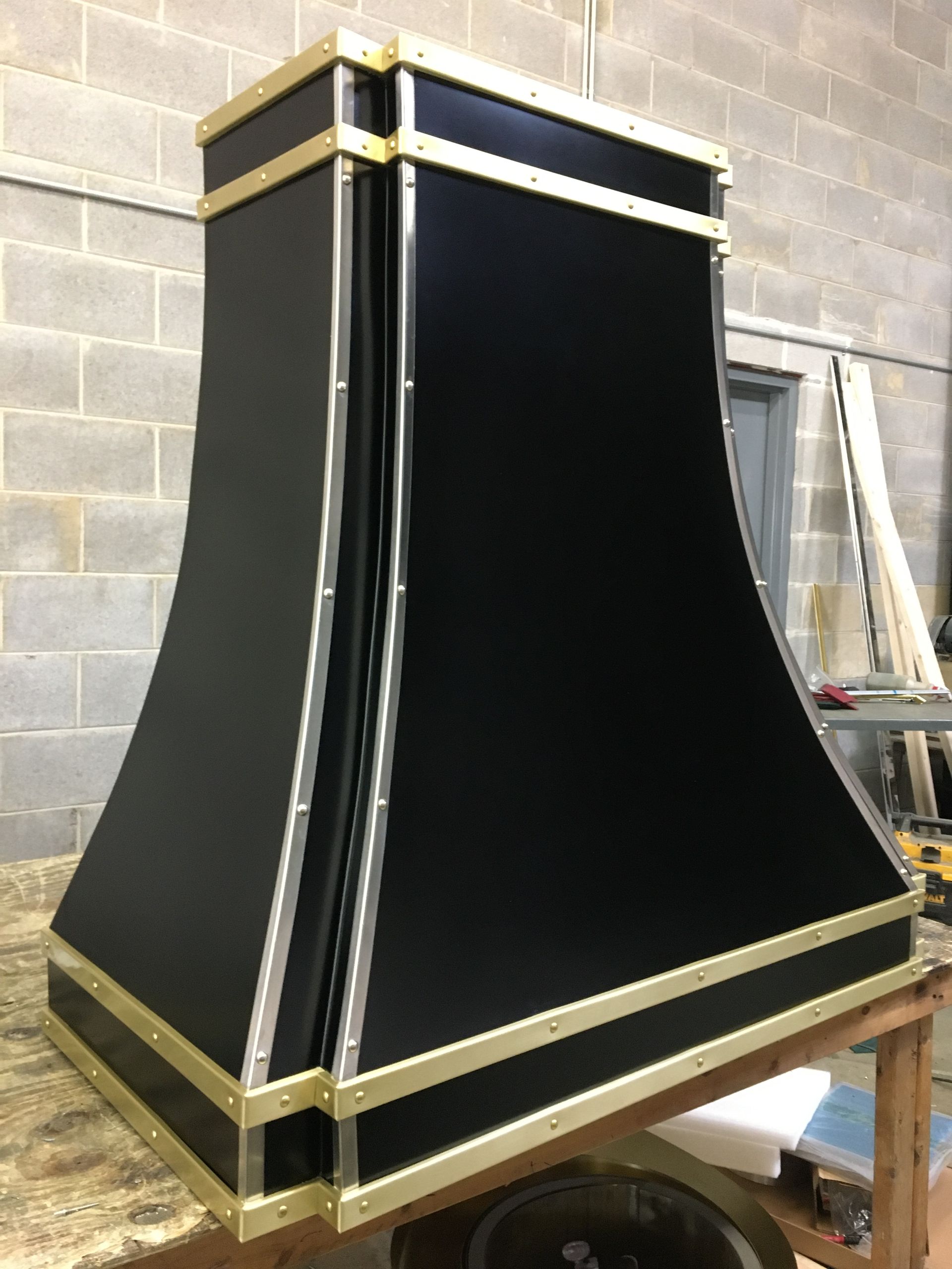 A black and gold hood is sitting on top of a wooden table.