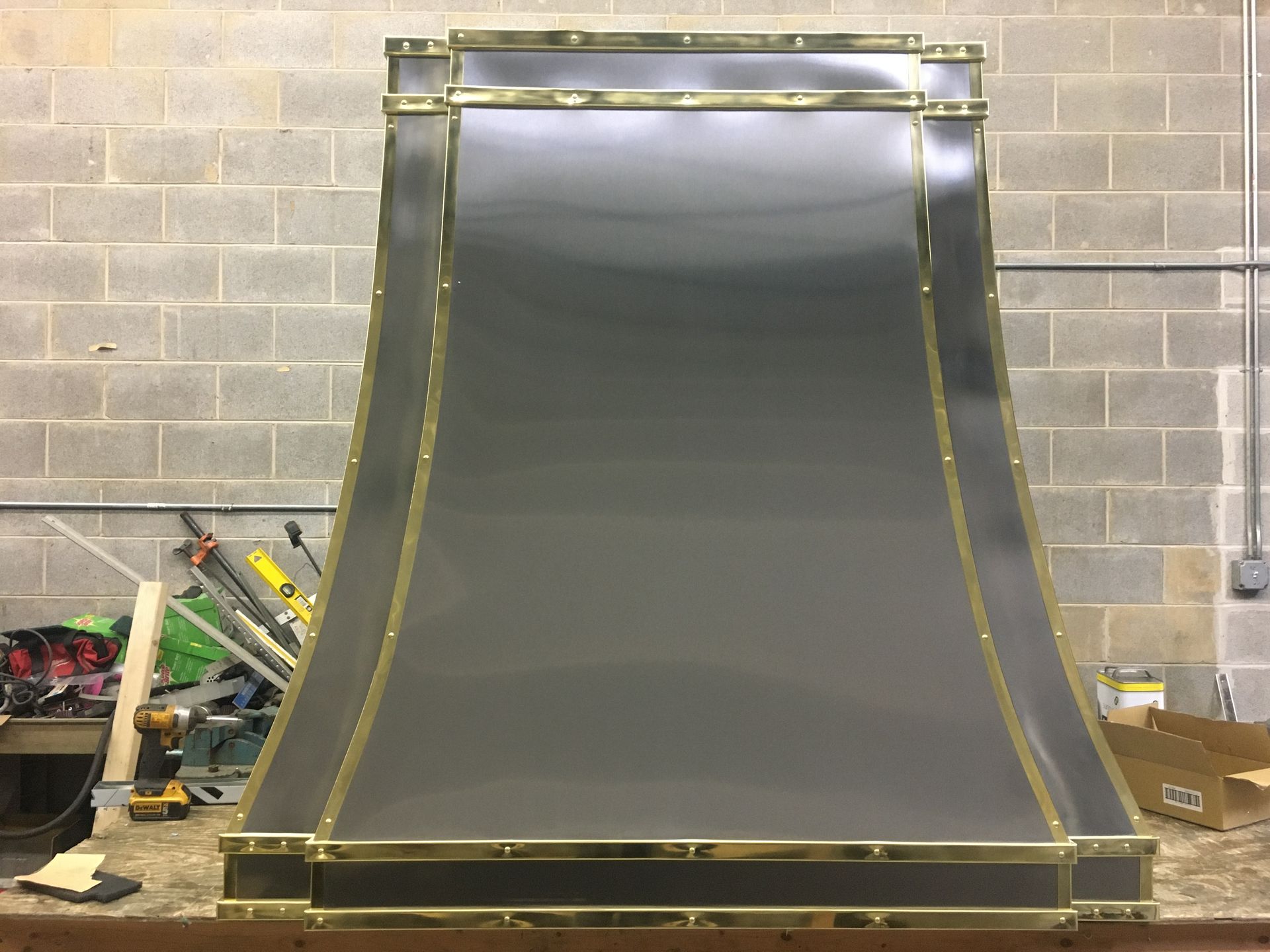 A stainless steel hood is sitting on a counter in front of a brick wall