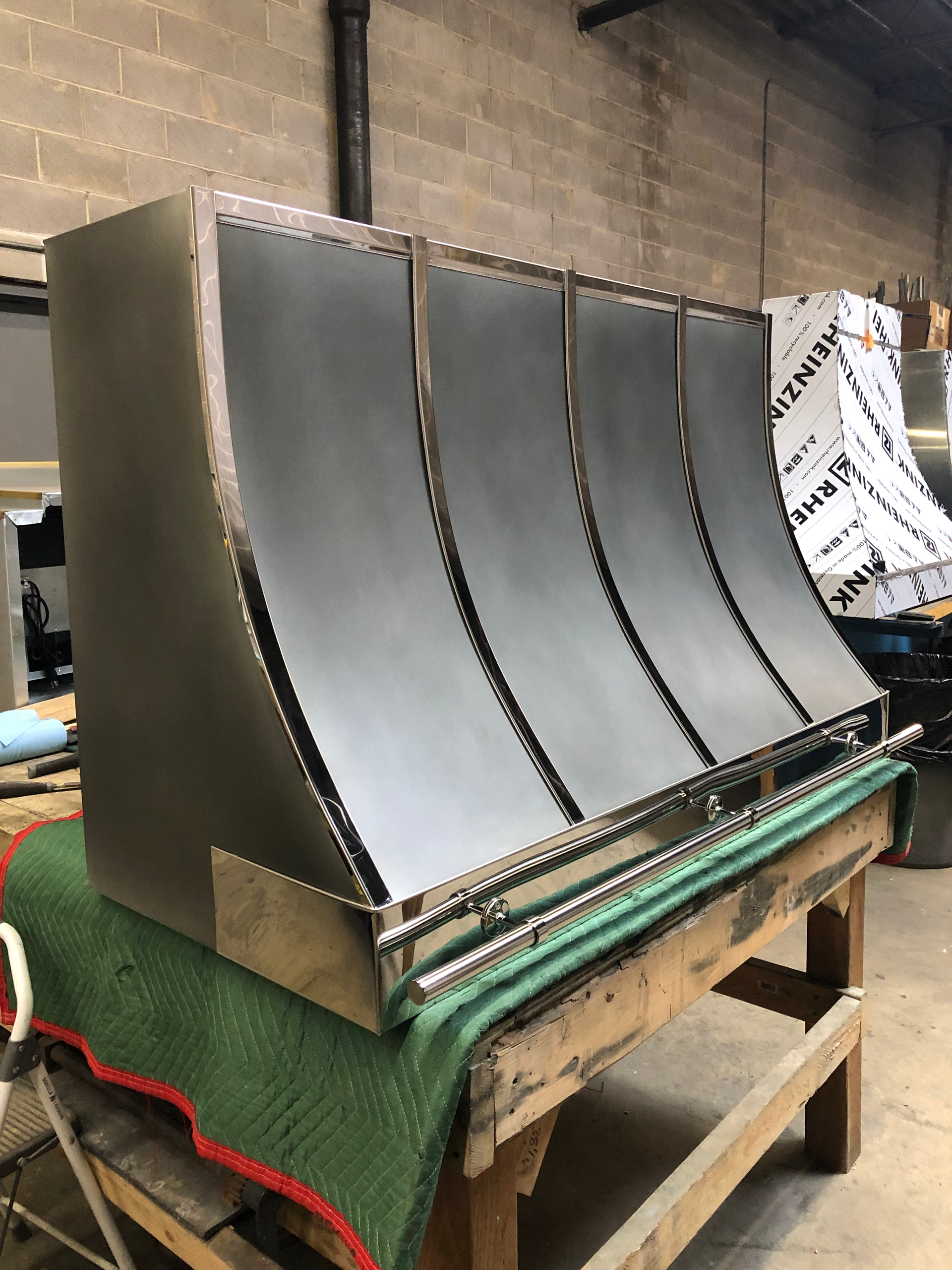A stainless steel hood is sitting on top of a wooden table.