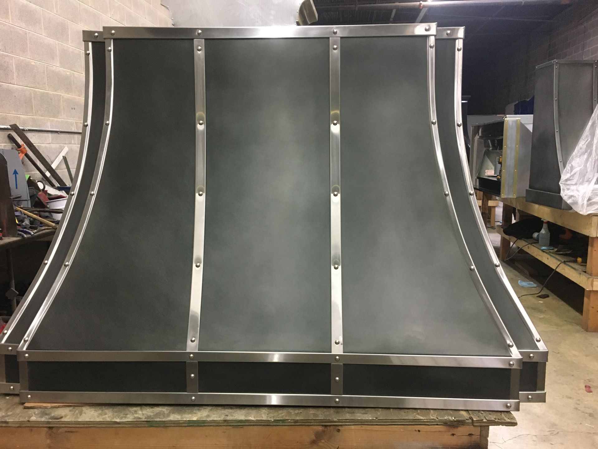 A stainless steel hood is sitting on top of a wooden table.