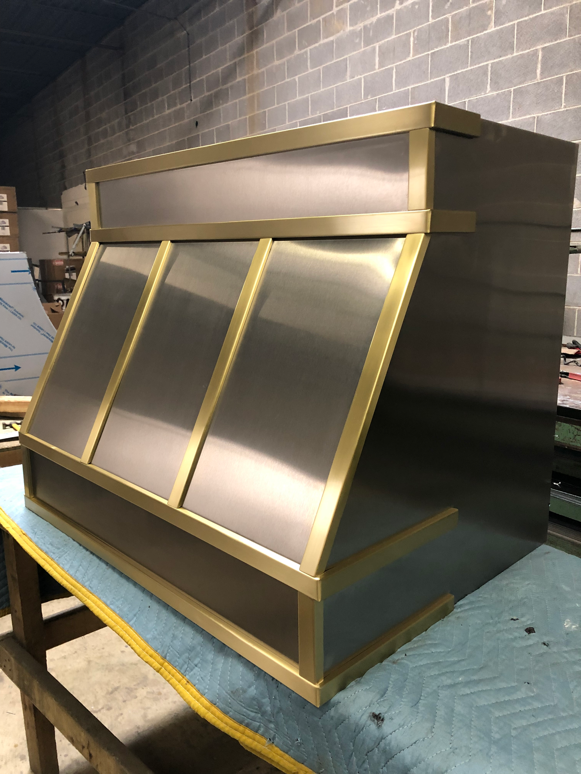 A stainless steel hood with brass trim is sitting on a table.