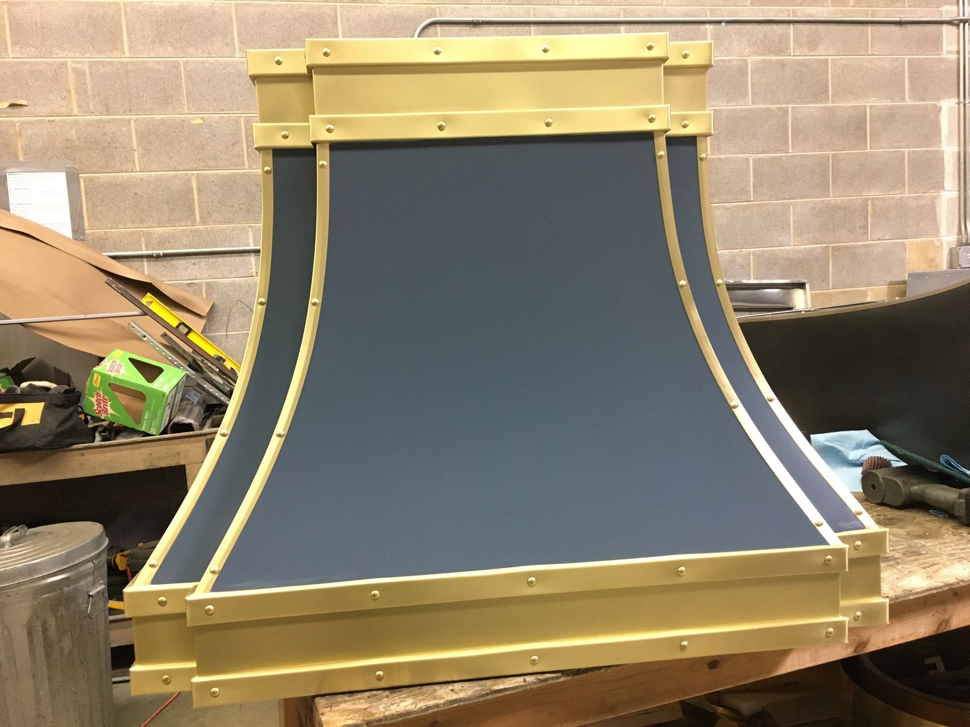 A black and gold hood is sitting on a wooden table.