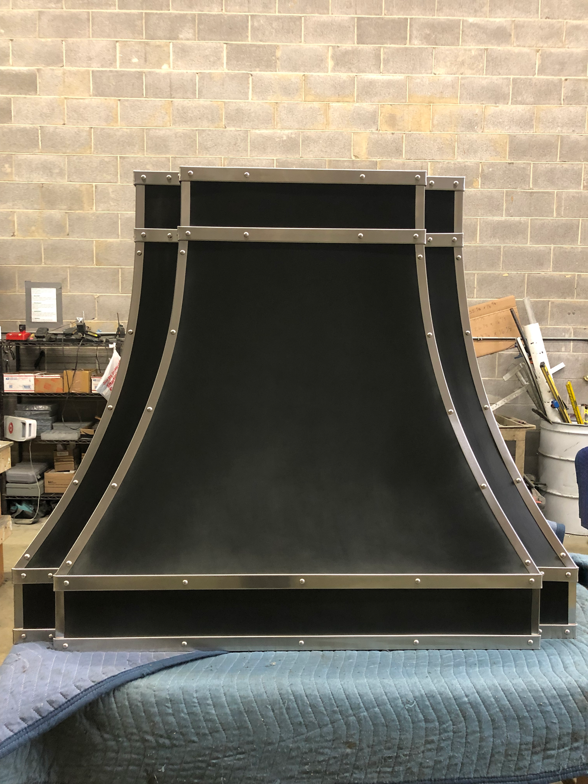 A black hood is sitting on top of a blue blanket in front of a brick wall.