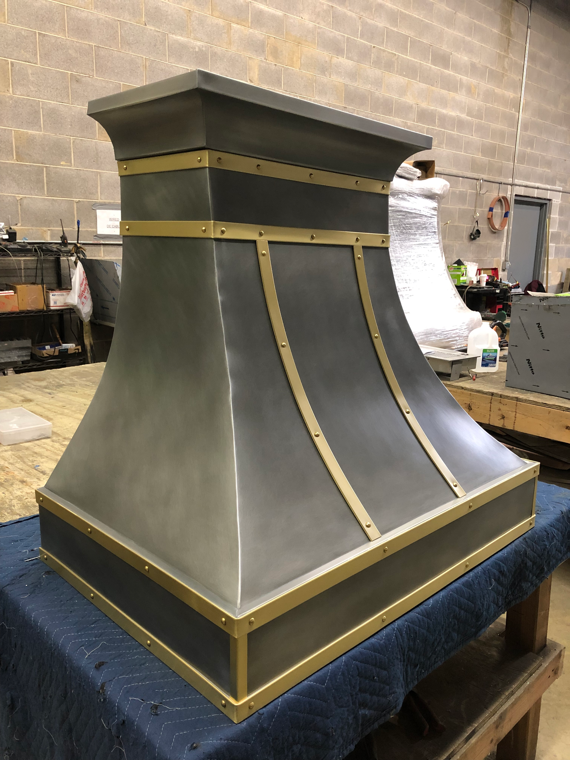 A stainless steel hood with brass trim is sitting on a table.