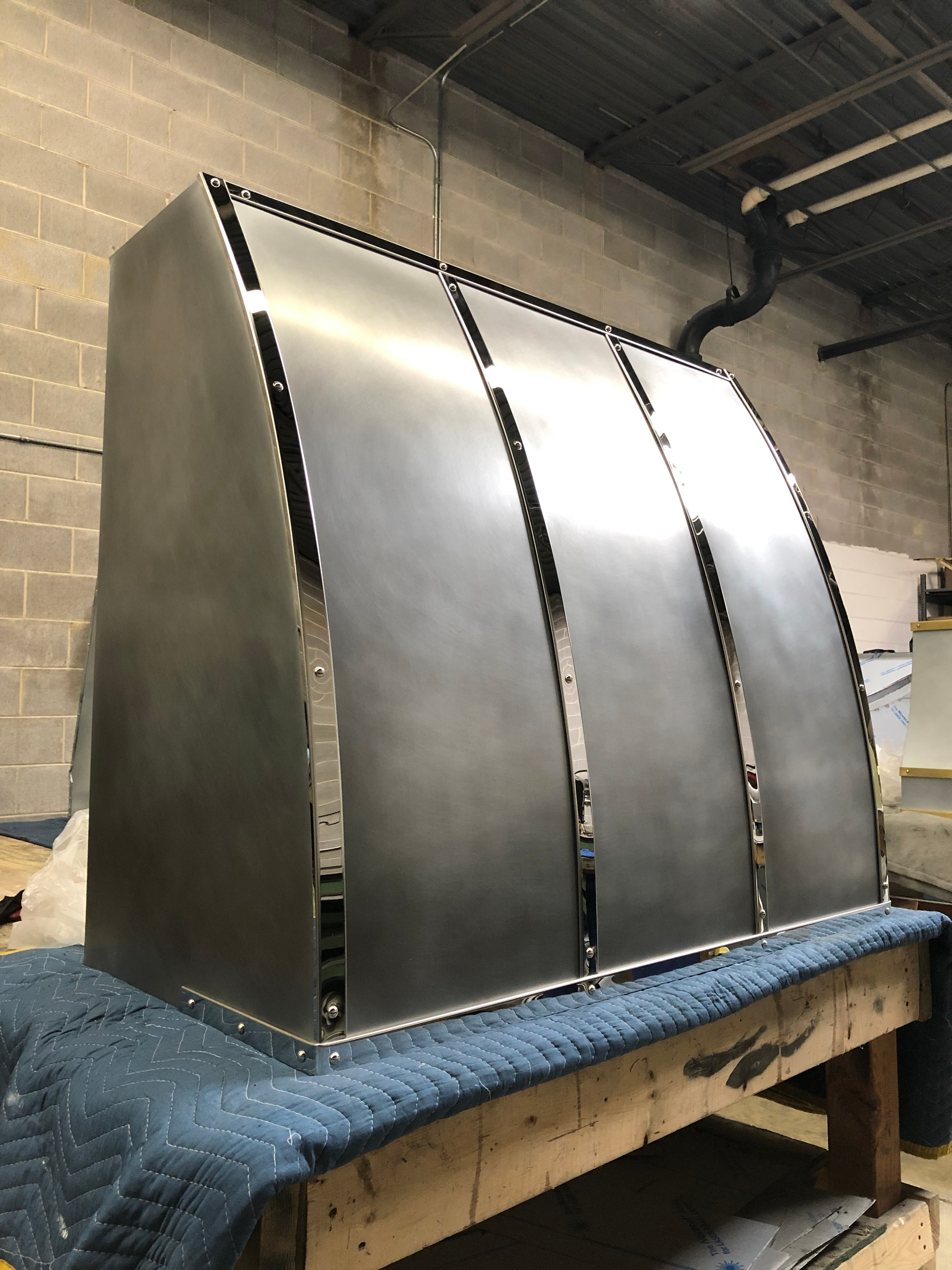 A stainless steel hood is sitting on top of a wooden table.