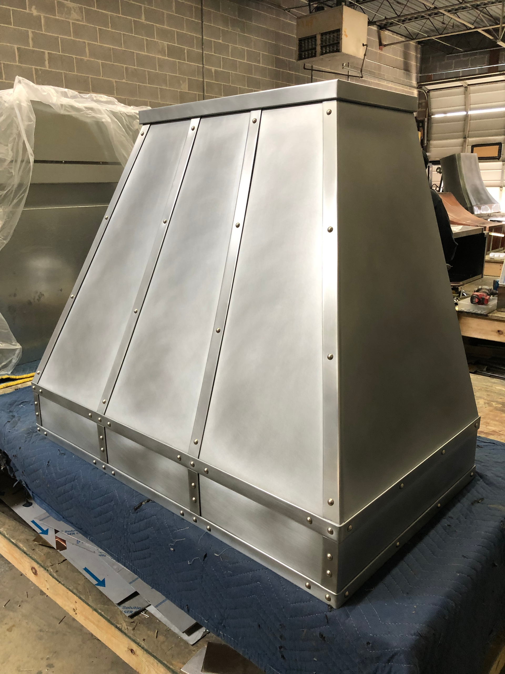 A stainless steel hood is sitting on top of a blue table.