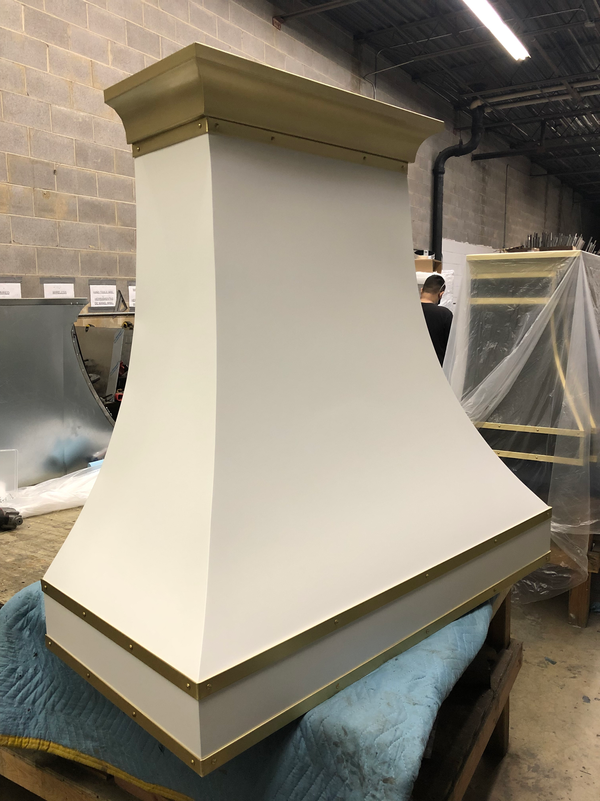 A white hood is sitting on top of a wooden pallet in a warehouse.