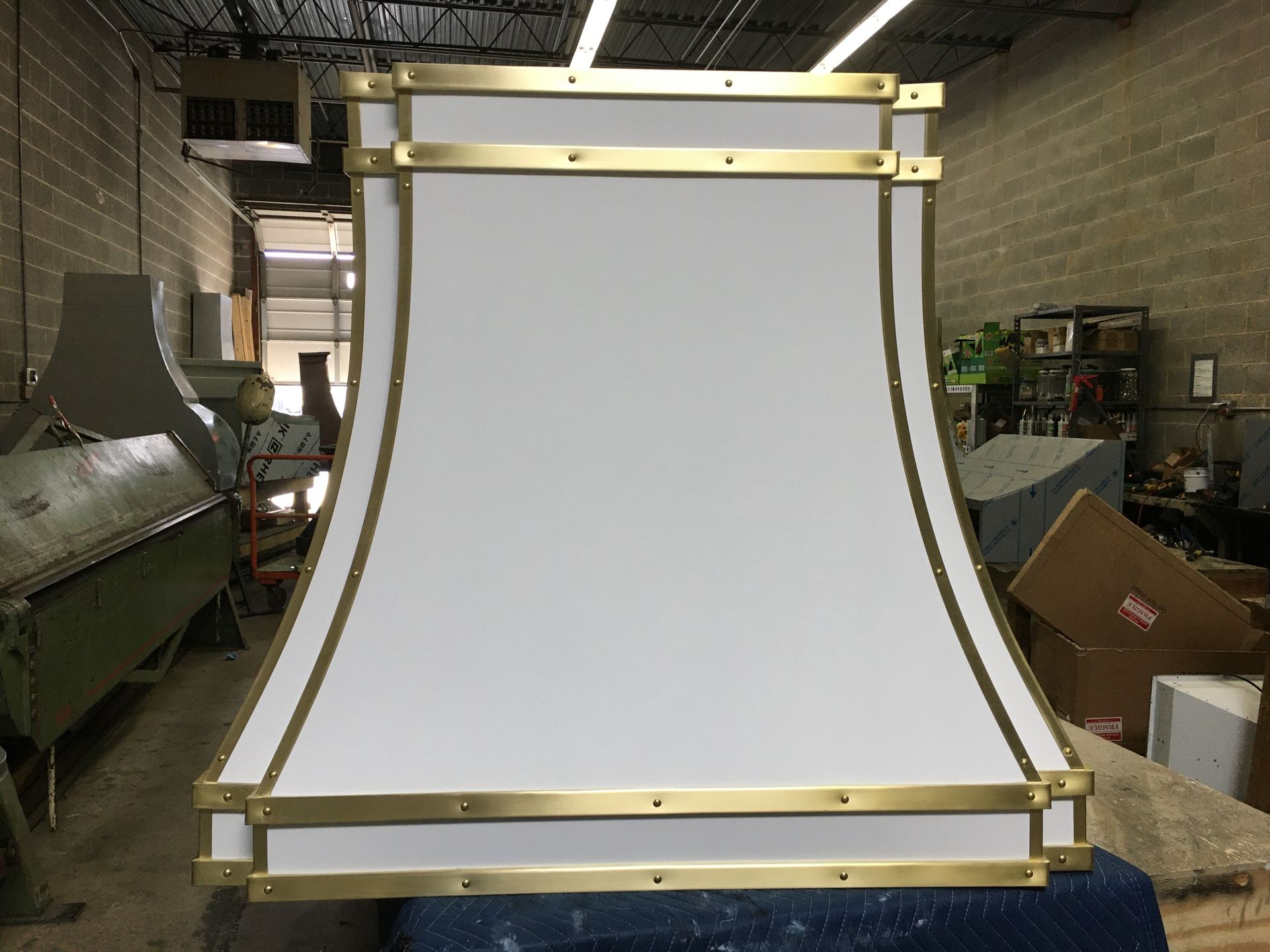 A white lampshade with brass trim is sitting on a table in a room.