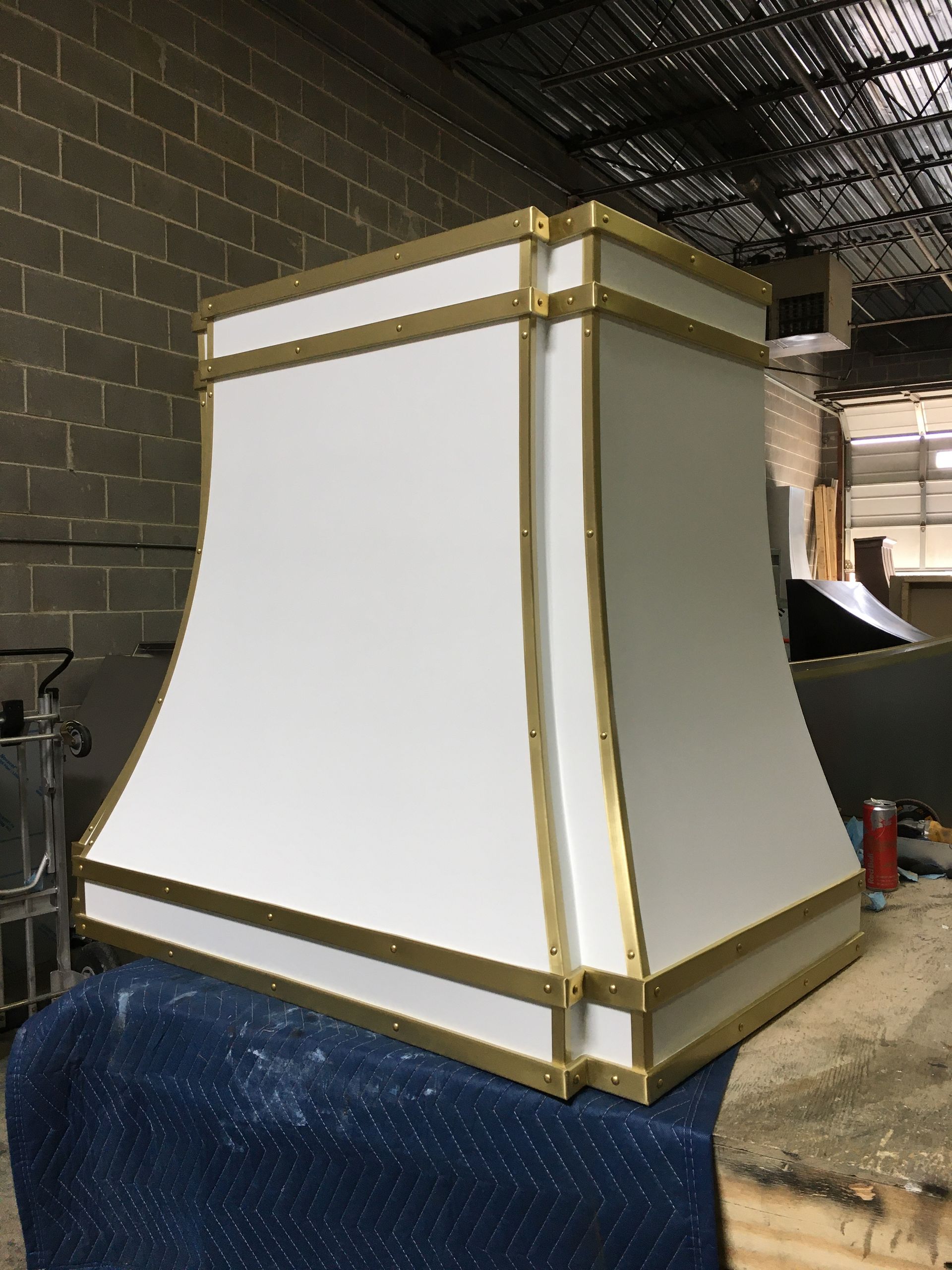 A white lampshade with brass trim is sitting on a table.