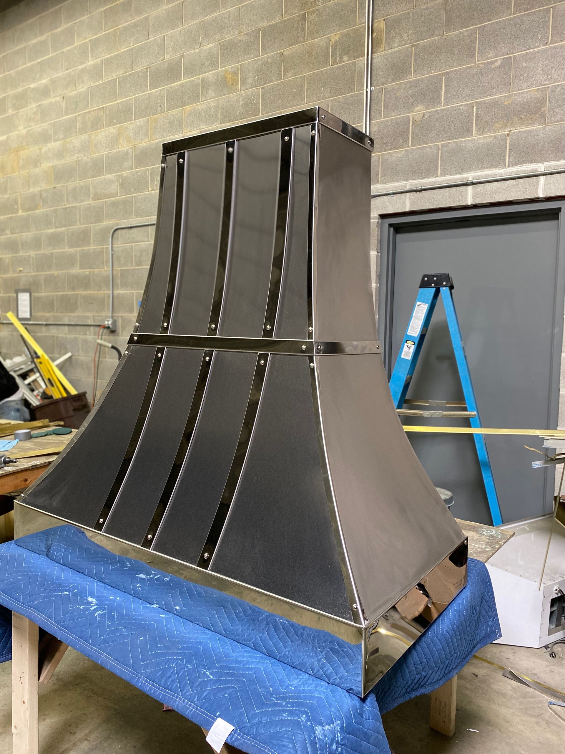 A stainless steel hood is sitting on top of a blue table.