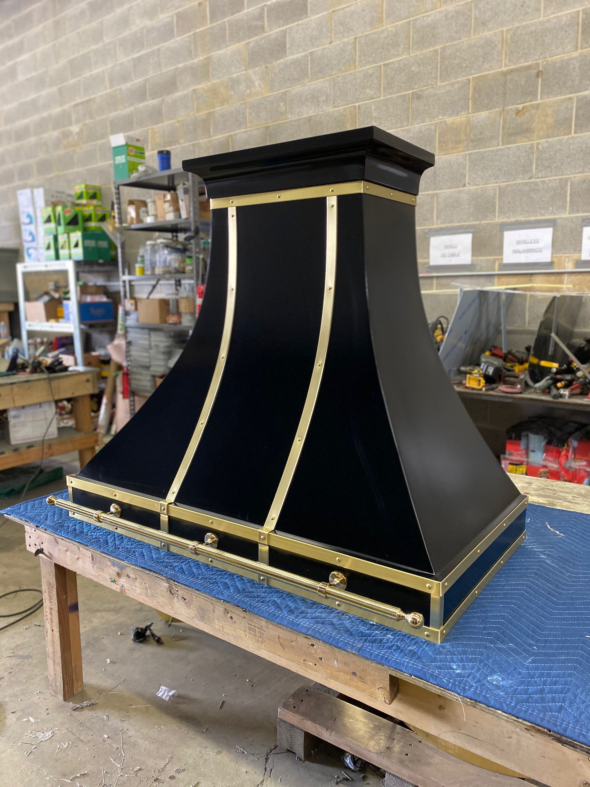 A black and gold hood is sitting on a wooden table.
