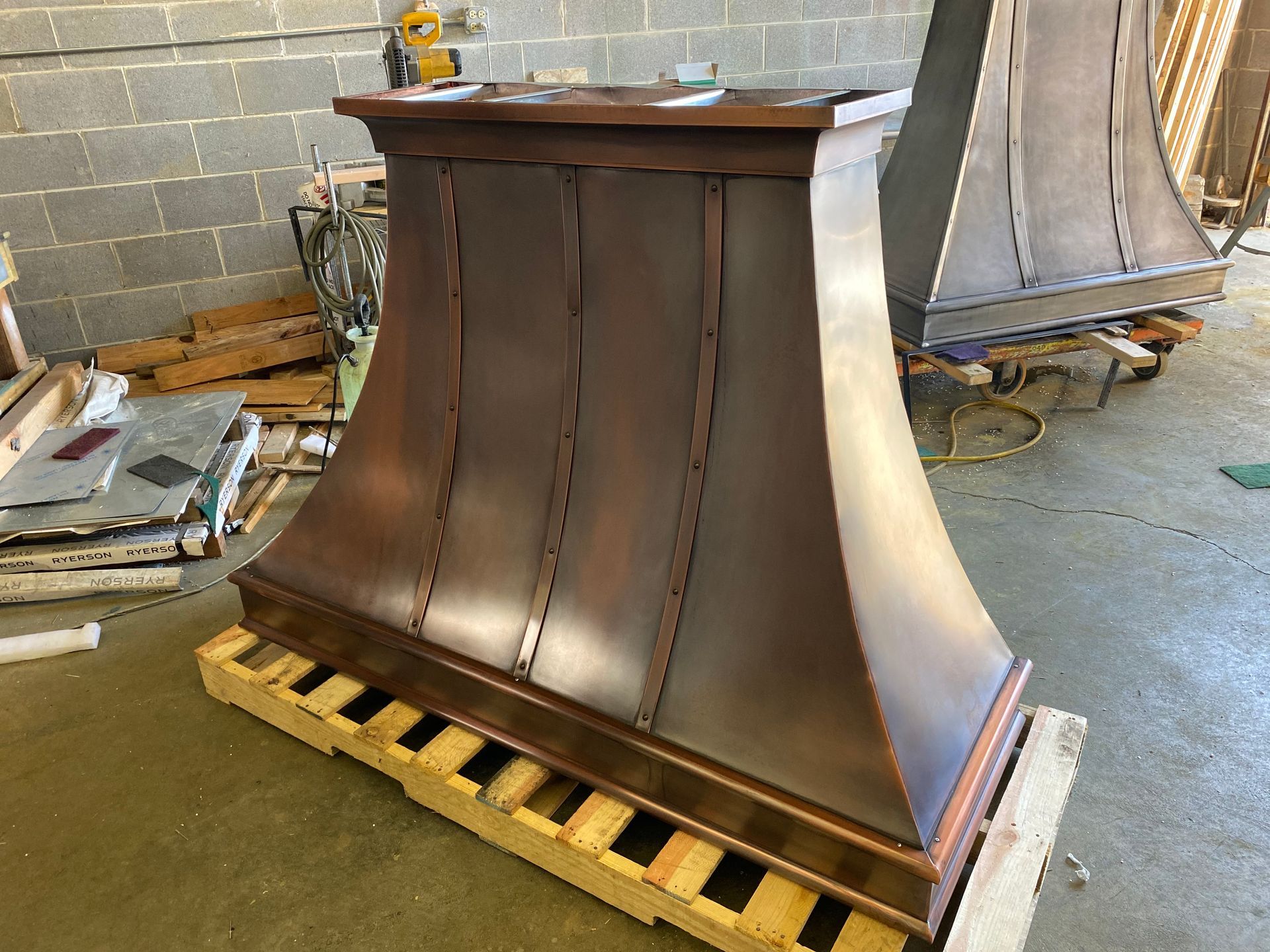 A copper hood is sitting on top of a wooden pallet.