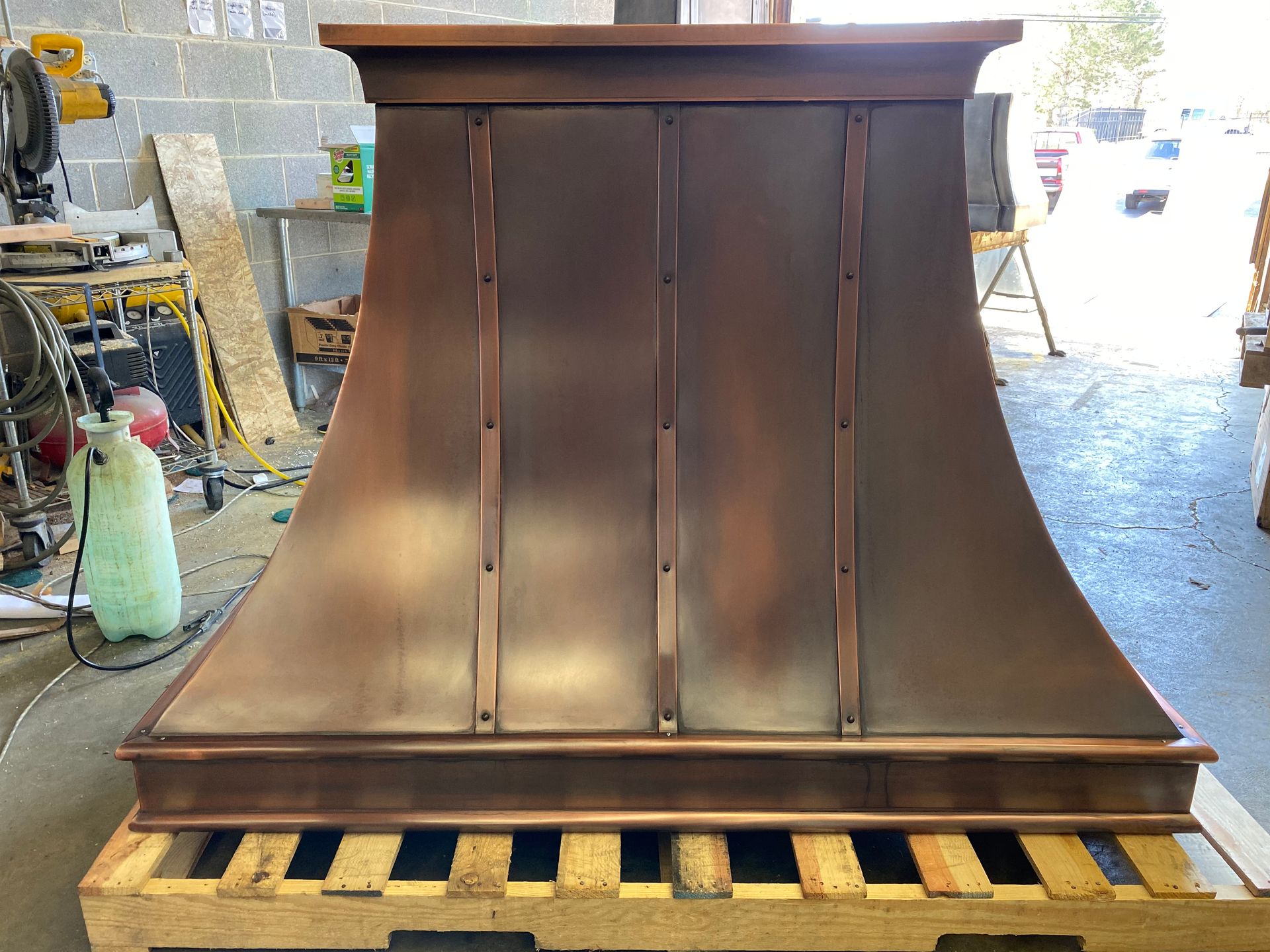 A copper hood is sitting on top of a wooden pallet.
