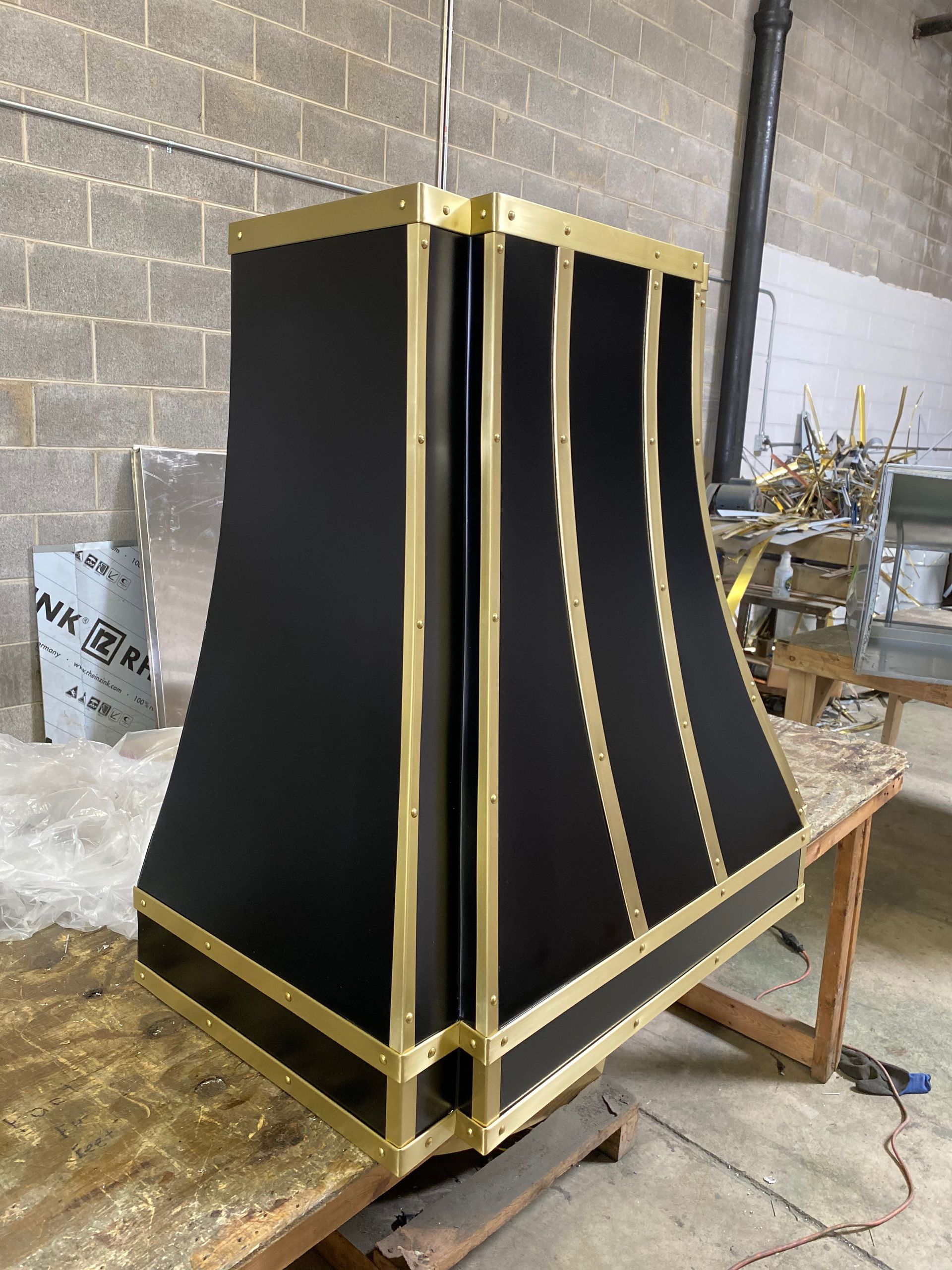 A black and gold hood is sitting on top of a wooden table.