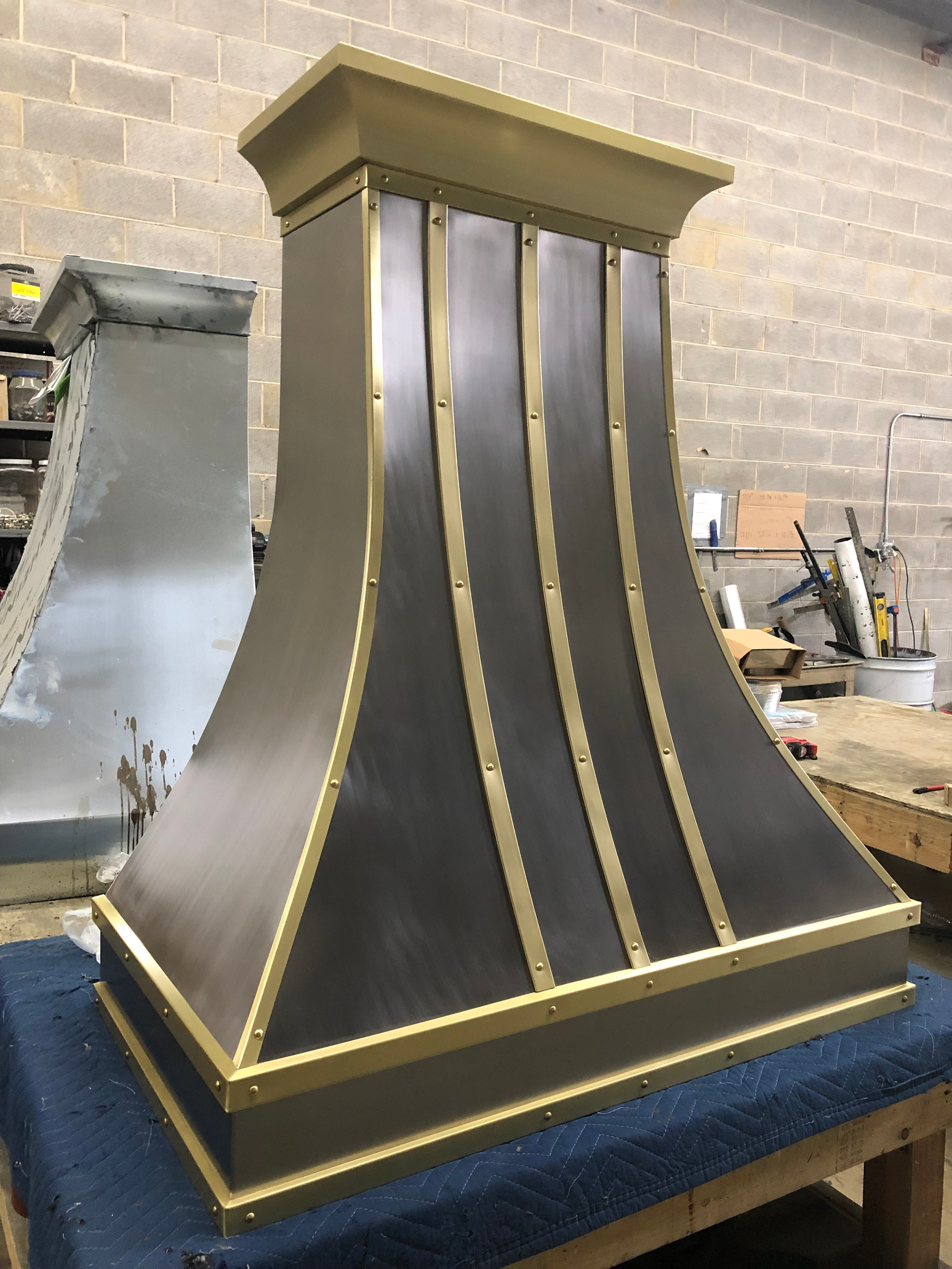 A stainless steel hood with gold trim is sitting on a table.
