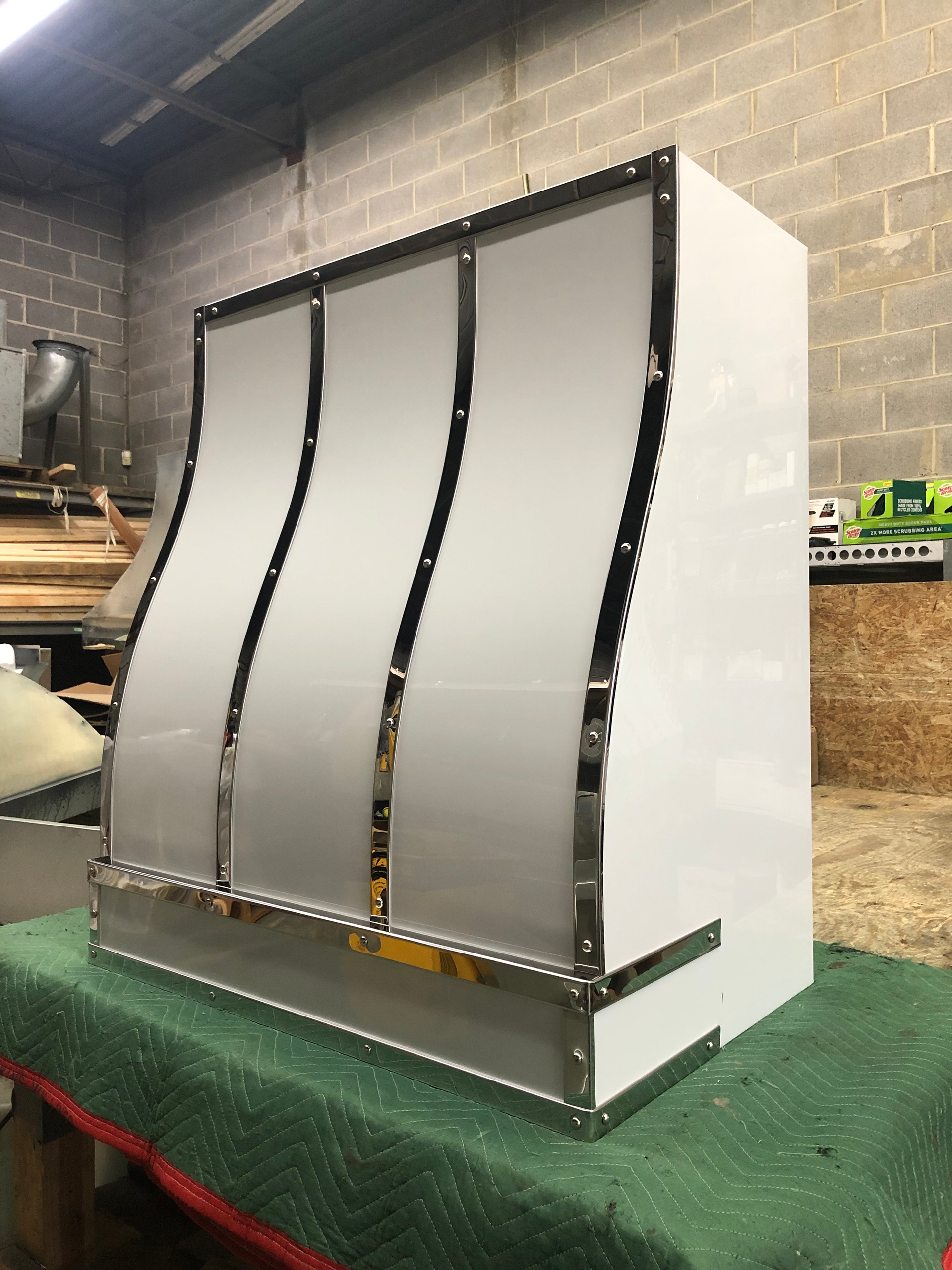 A stainless steel hood is sitting on top of a green table.