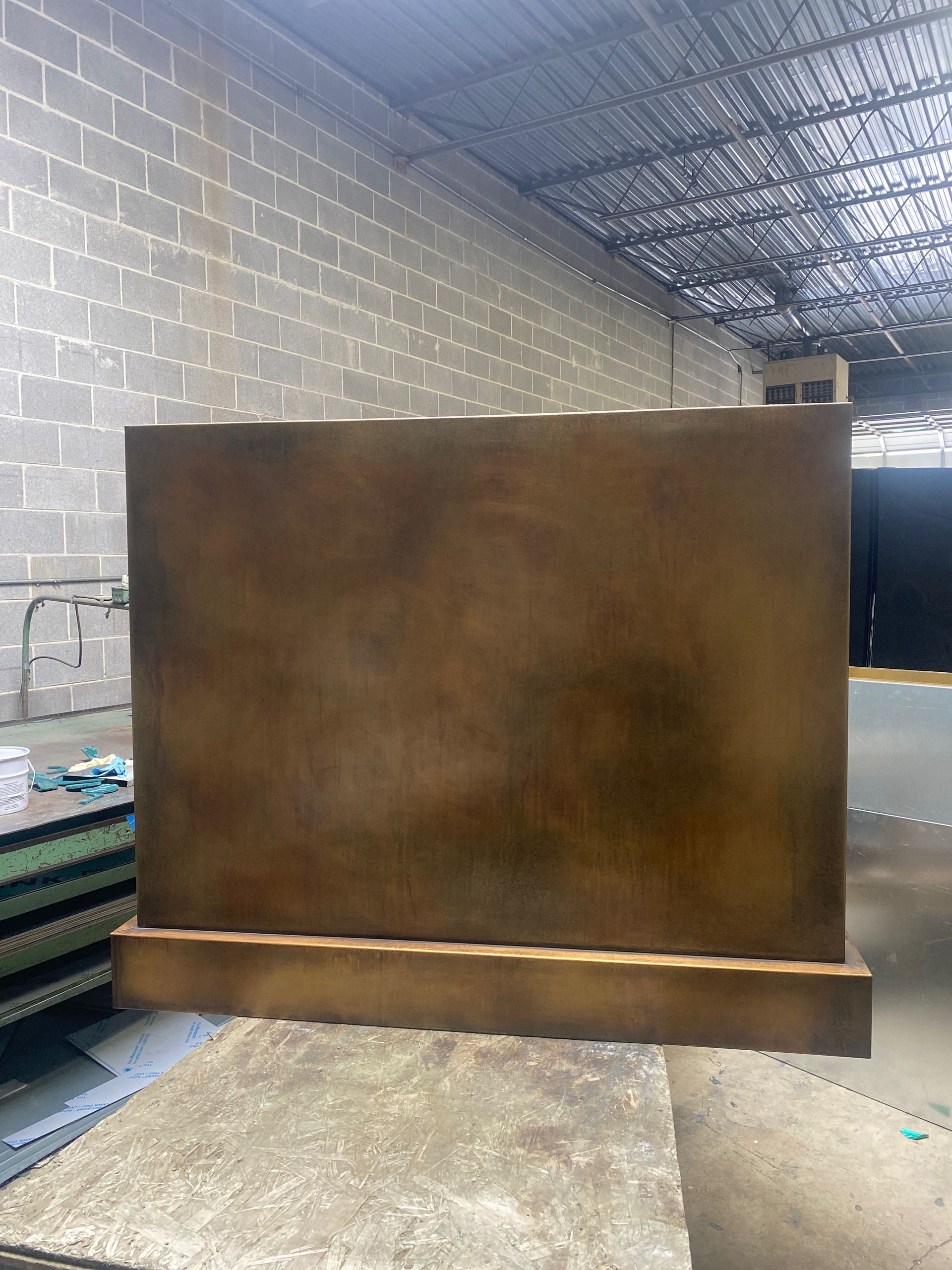 A large piece of metal is sitting on top of a wooden table in a warehouse.