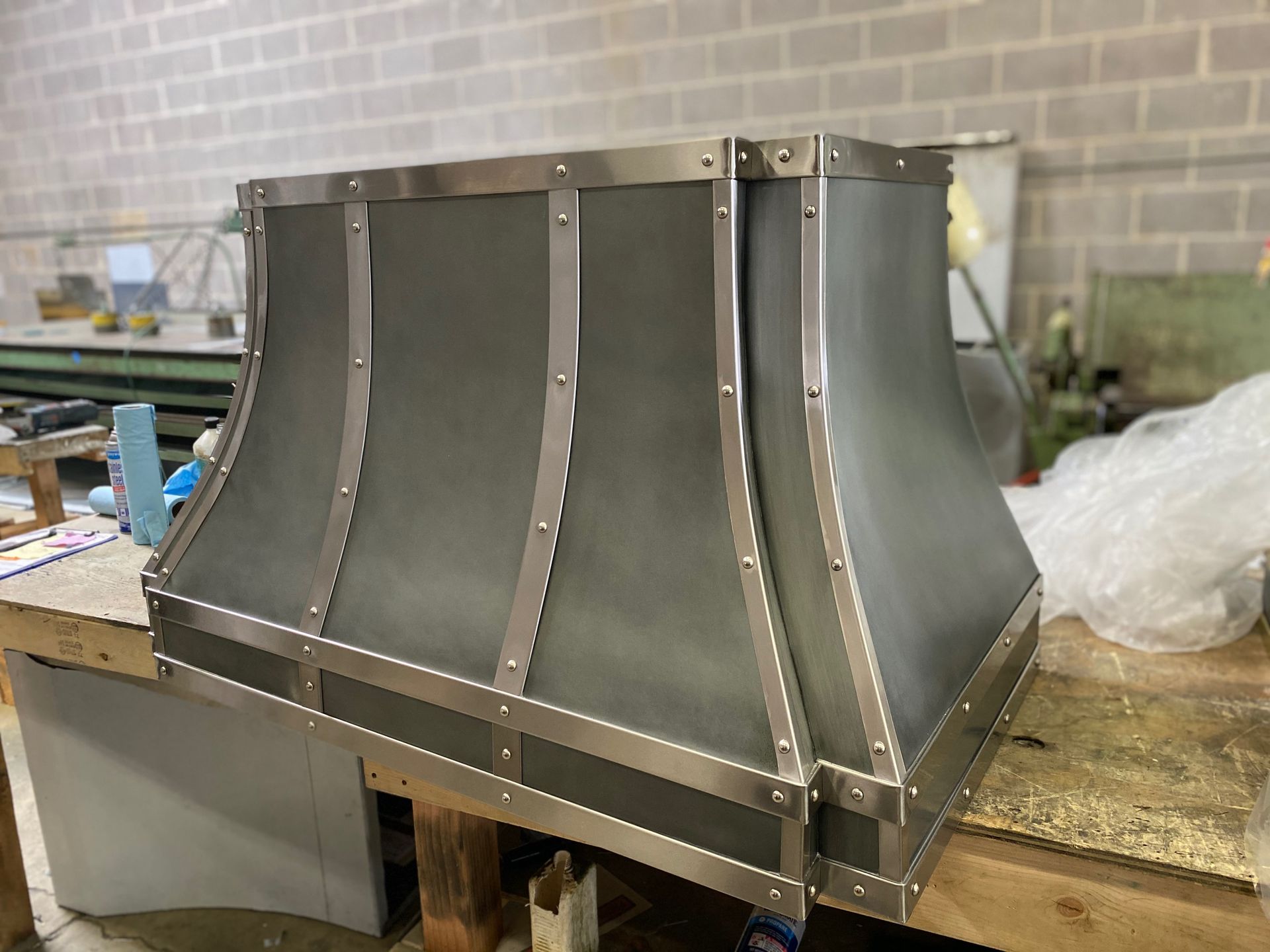 A stainless steel hood is sitting on top of a wooden table.