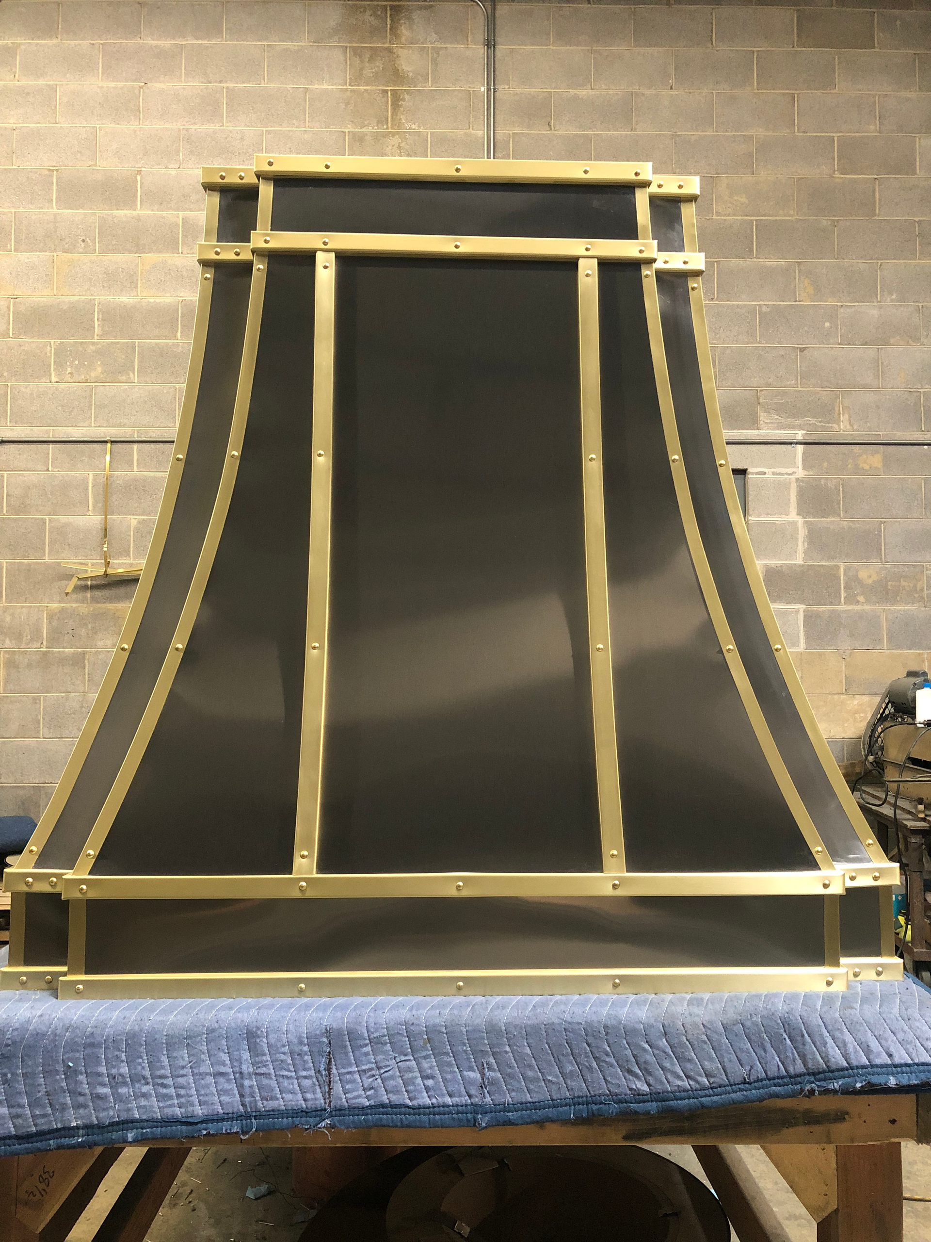 A black and gold hood is sitting on a table in front of a brick wall.