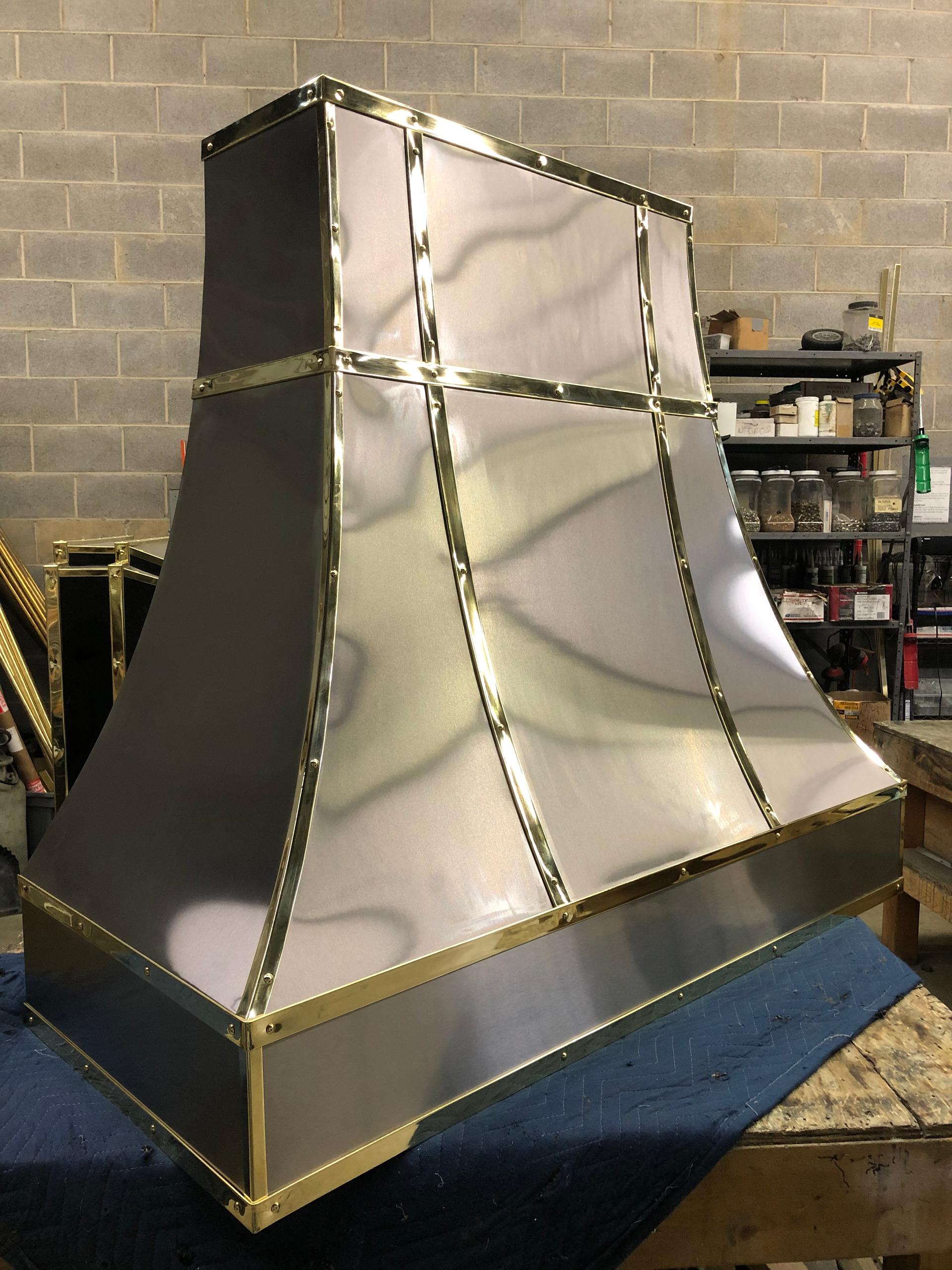 A stainless steel hood with gold trim is sitting on a table.
