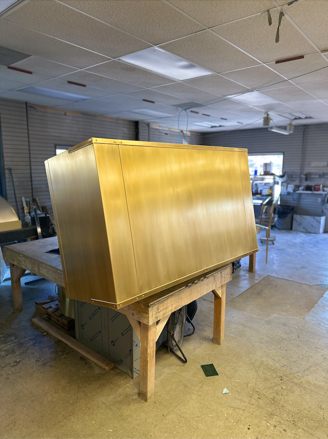 A large gold box is sitting on a wooden table in a room.