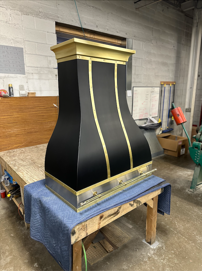 A black and gold hood is sitting on top of a wooden table.