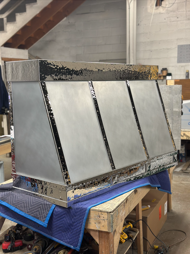 A stainless steel hood is sitting on top of a wooden table.