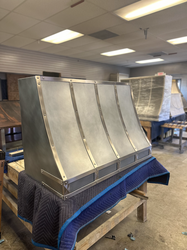 A stainless steel hood is sitting on top of a wooden table.
