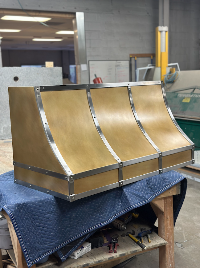 A brass hood is sitting on a blue blanket on a table