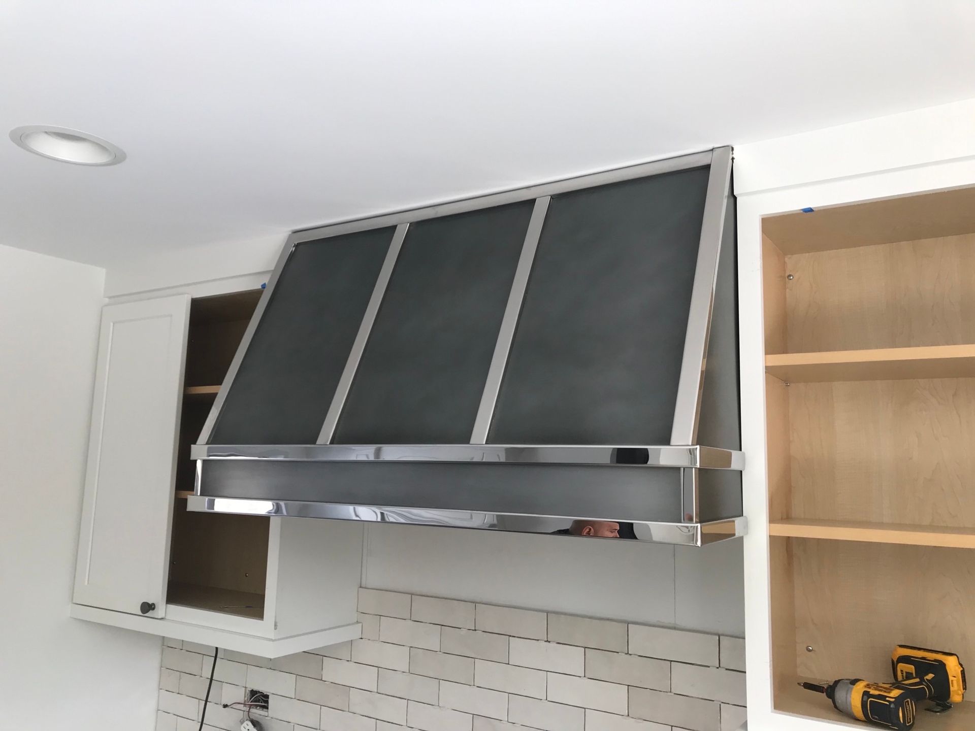 A stainless steel hood is hanging from the ceiling in a kitchen.
