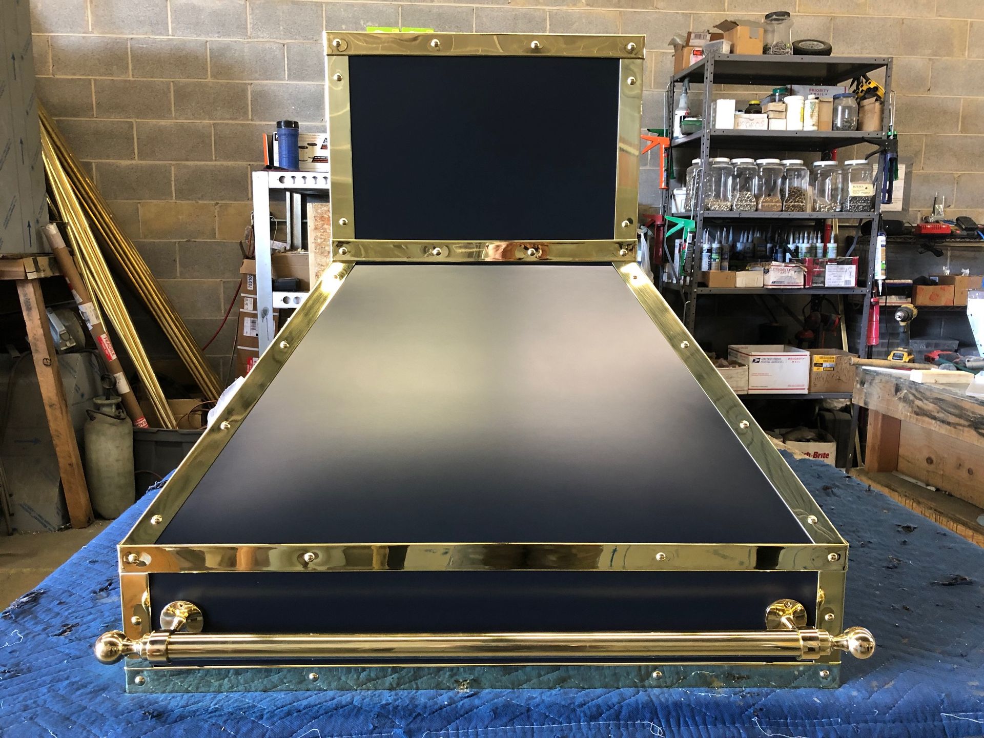 A black and gold stove hood is sitting on a blue table.