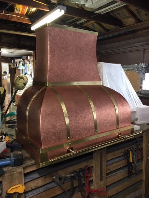 A large copper hood is sitting on top of a wooden table.