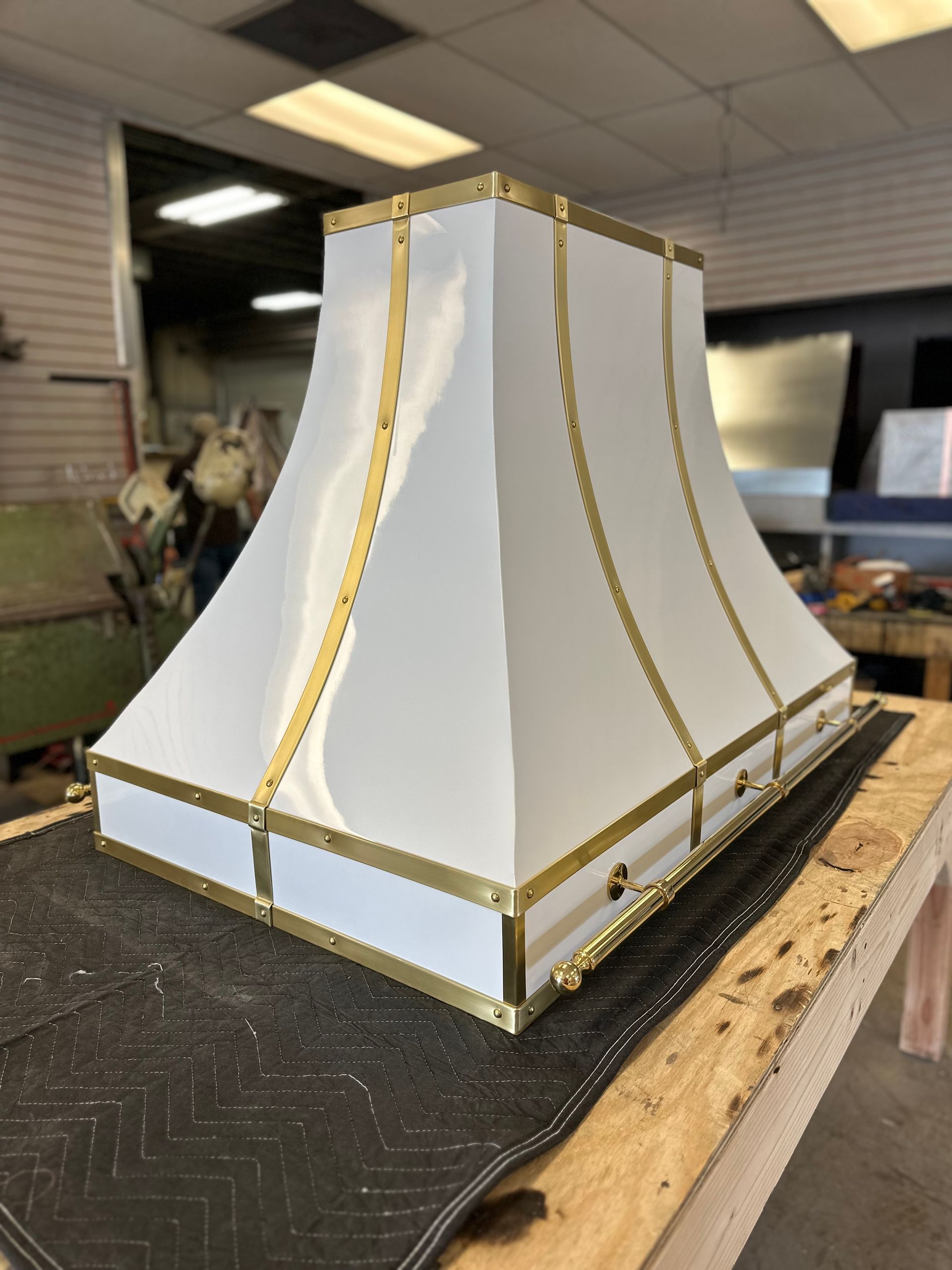 A white lamp shade with gold trim is sitting on a wooden table.
