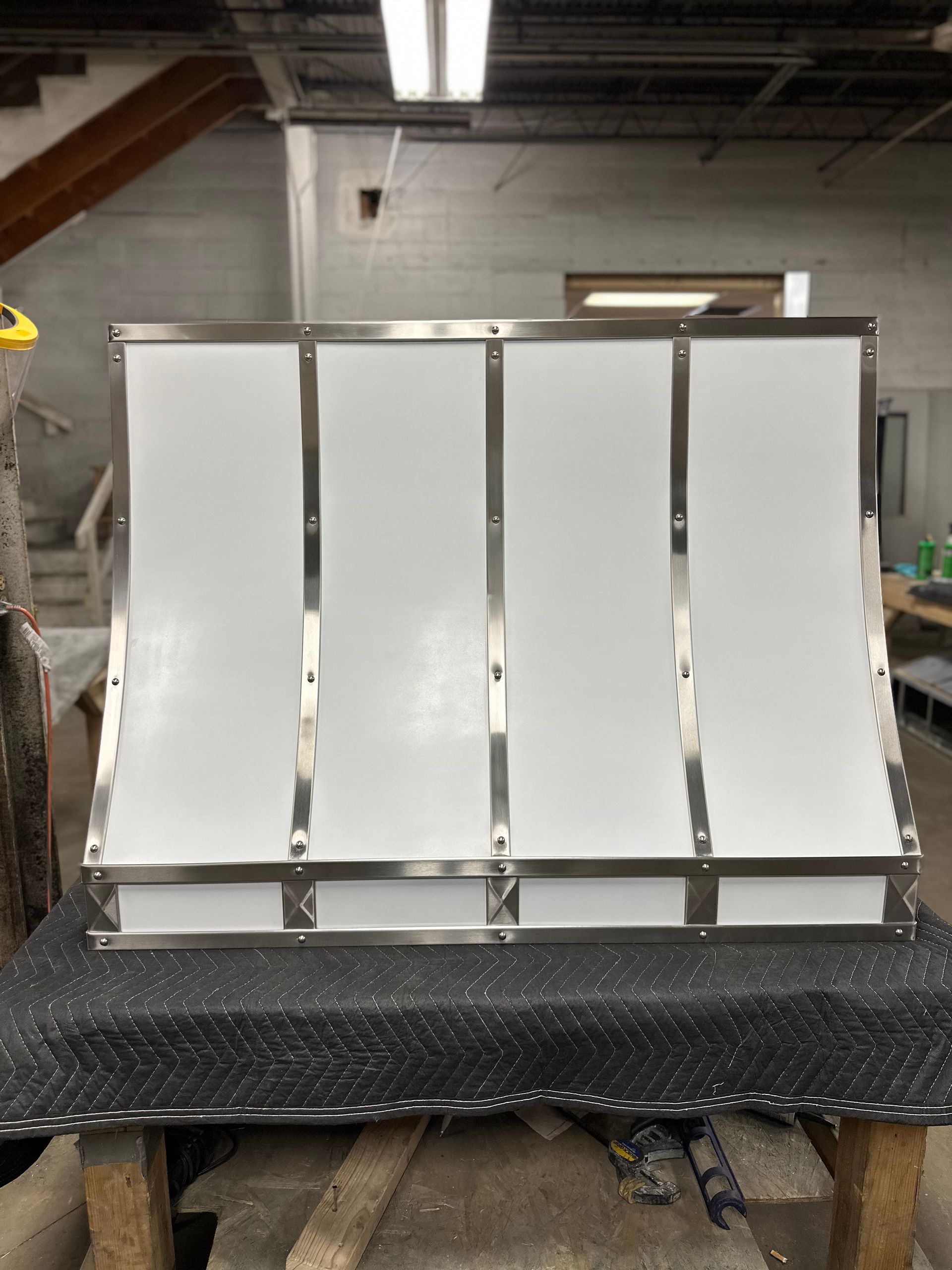 A stainless steel hood is sitting on top of a wooden table.