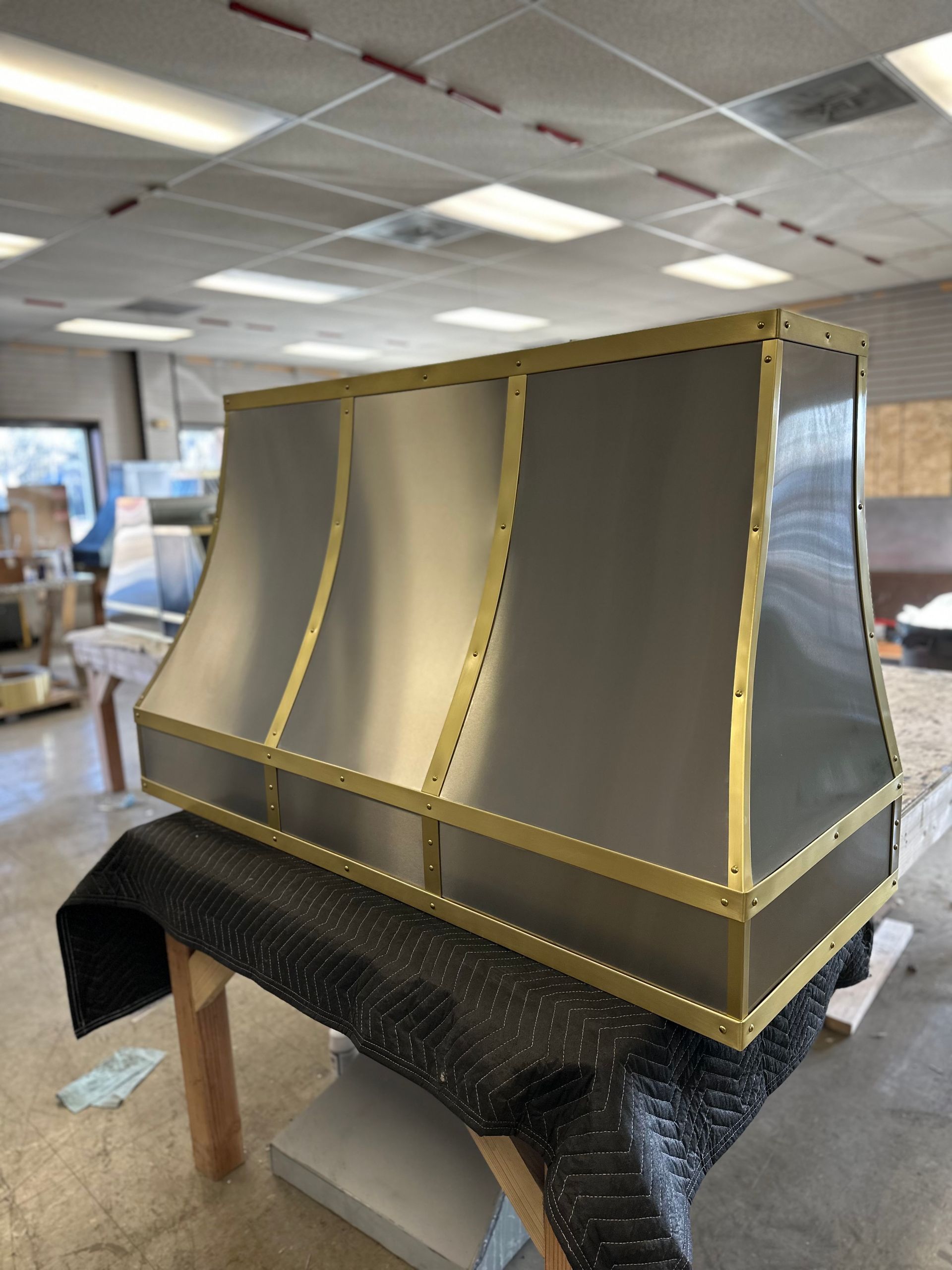 A stainless steel hood with gold trim is sitting on a table