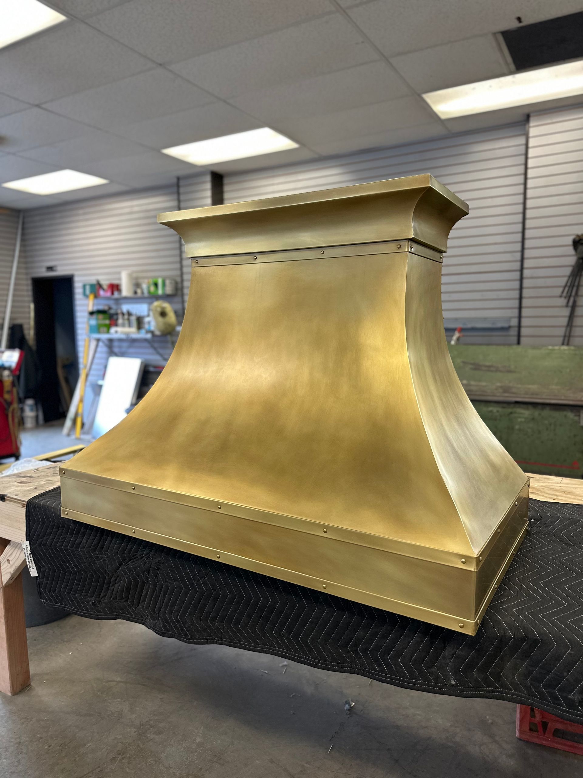 A brass hood is sitting on a table in a room.