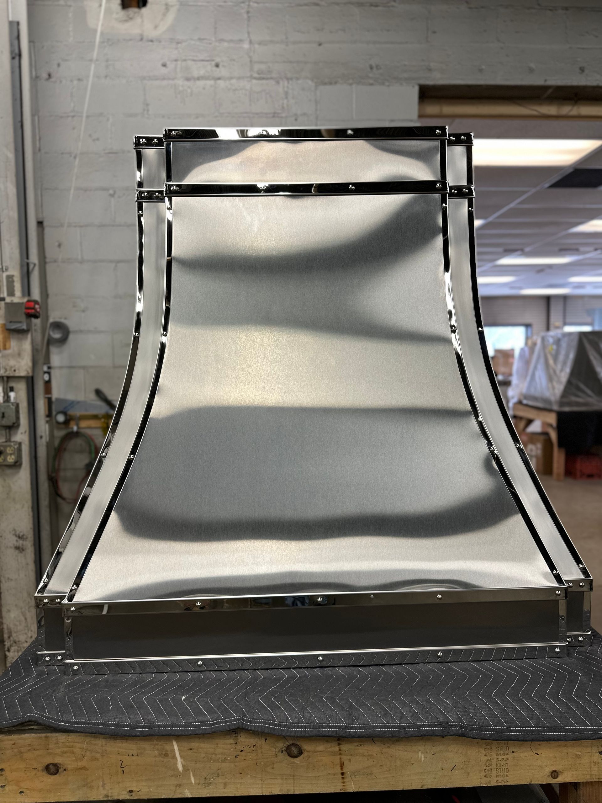 A stainless steel hood is sitting on a wooden table