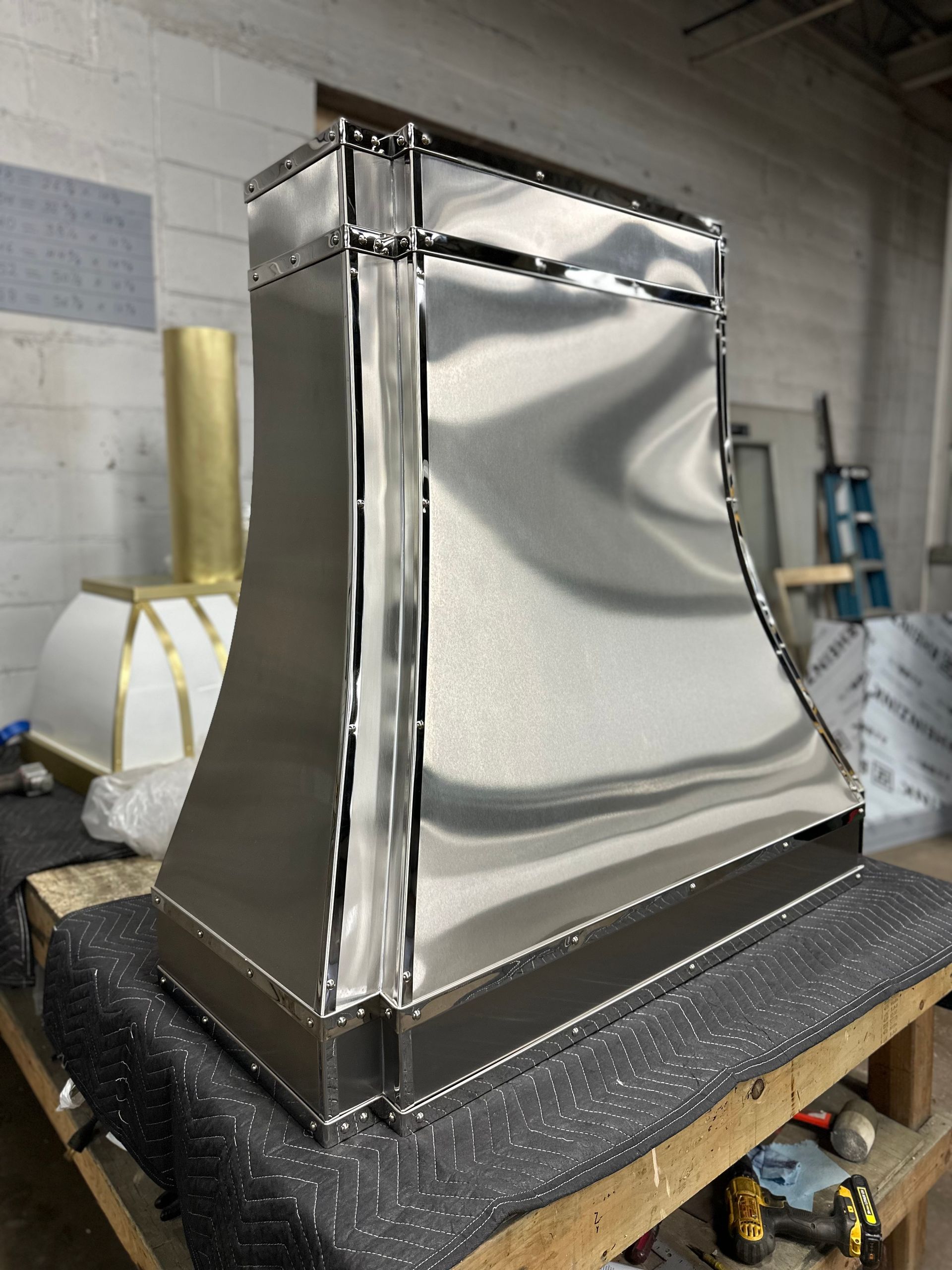 A stainless steel hood is sitting on top of a wooden table.