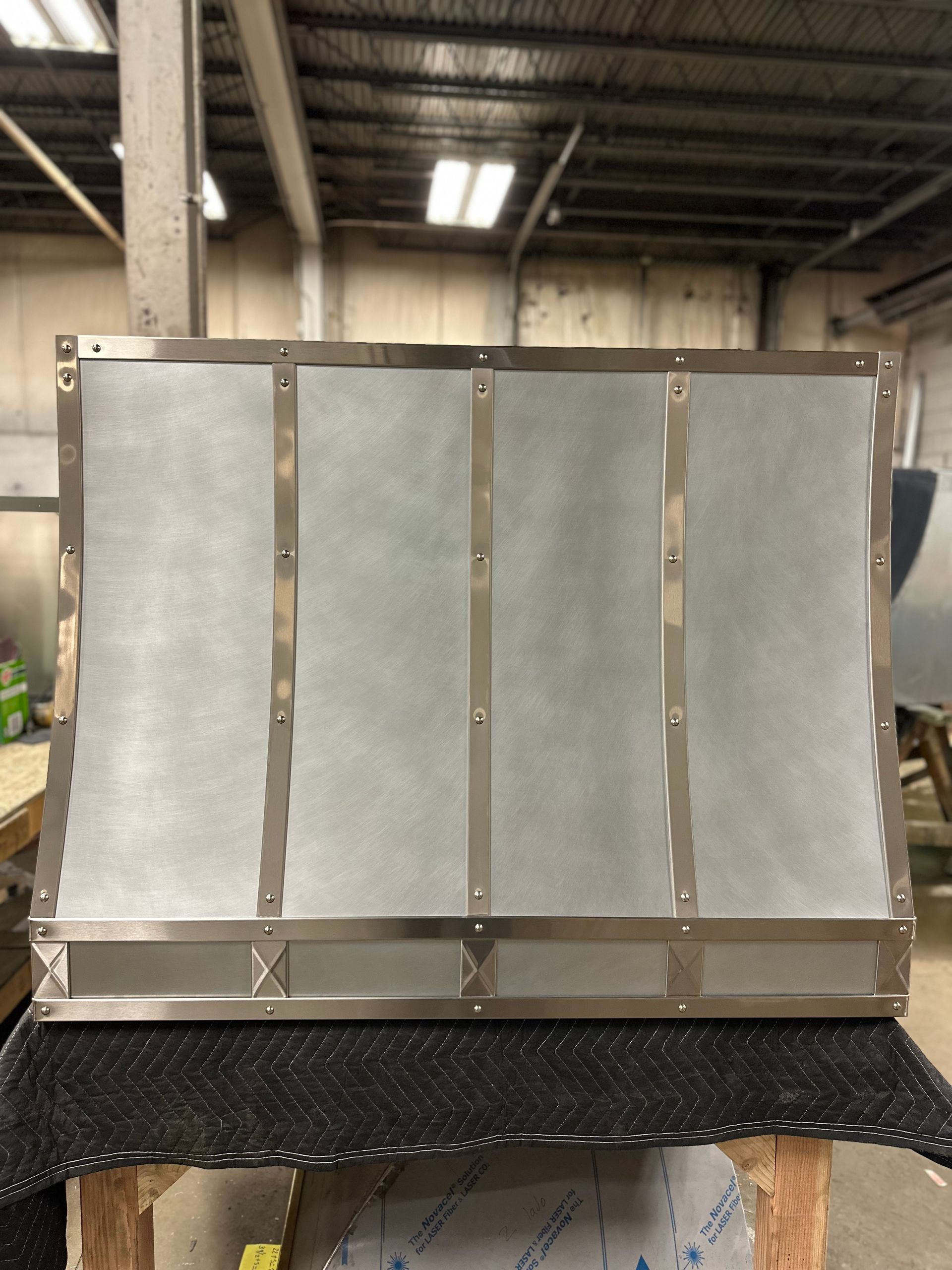 A stainless steel hood is sitting on a table in a warehouse.