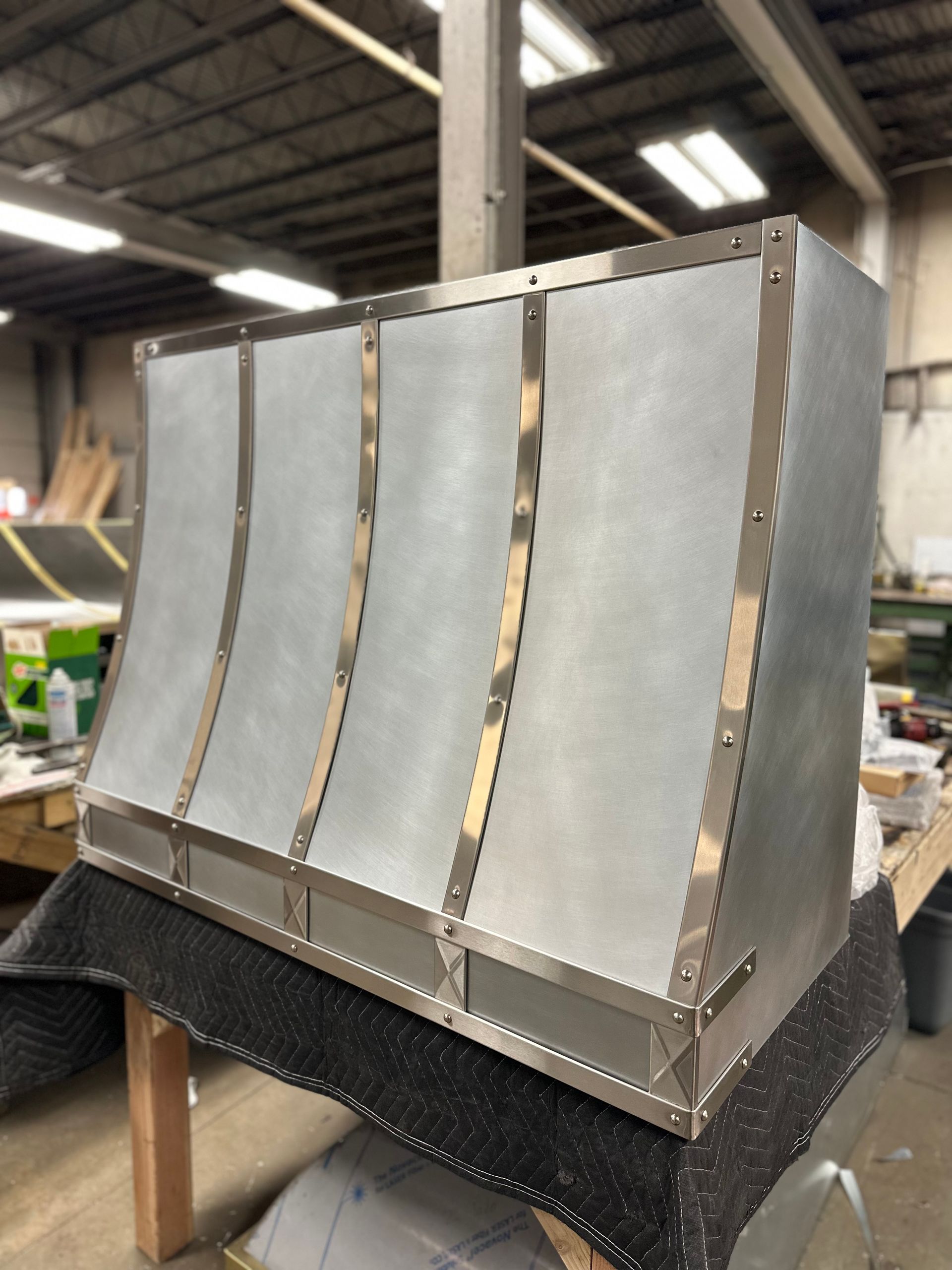 A stainless steel hood is sitting on a table in a warehouse.