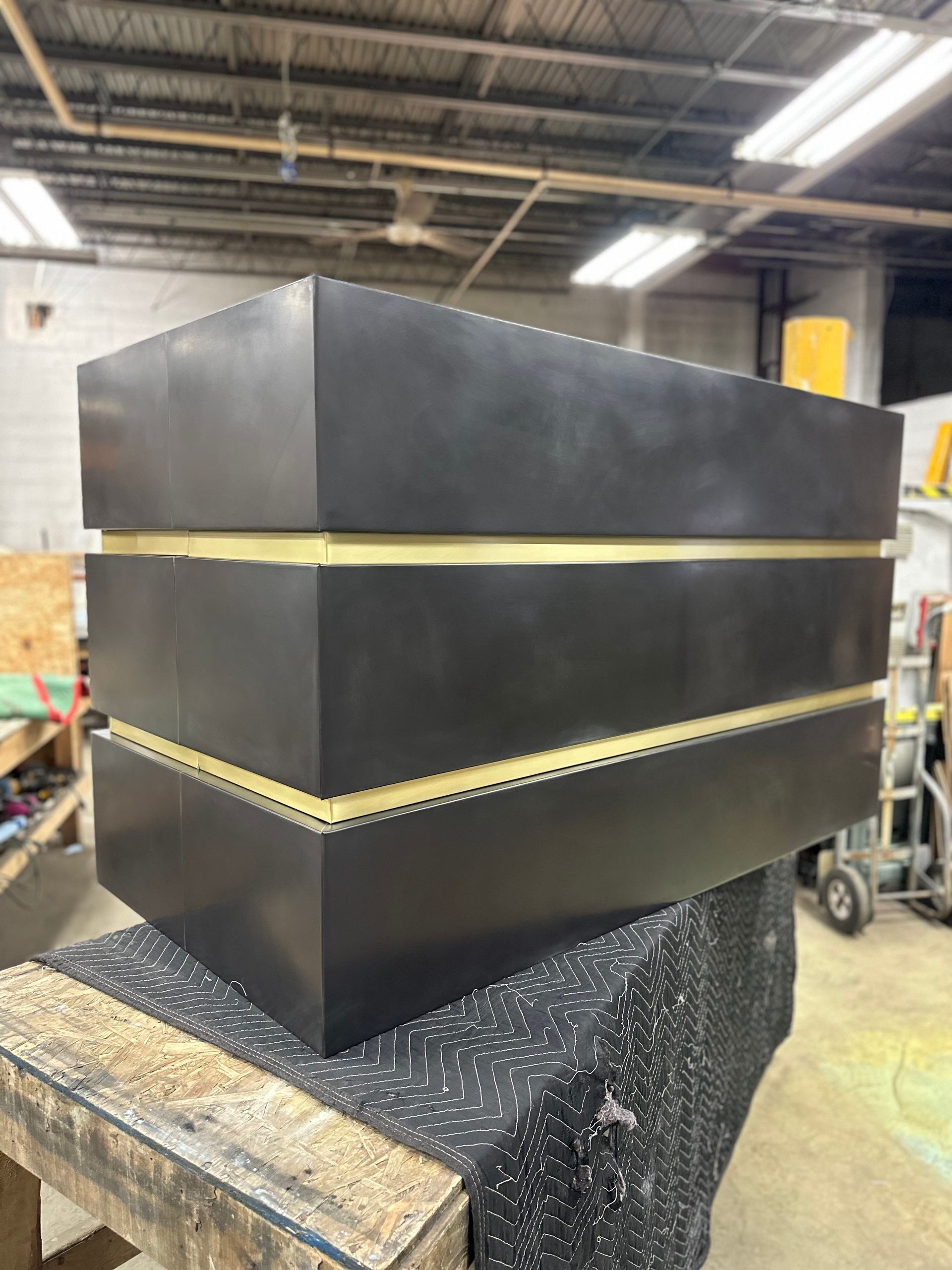 A black box with gold stripes is sitting on top of a wooden table.