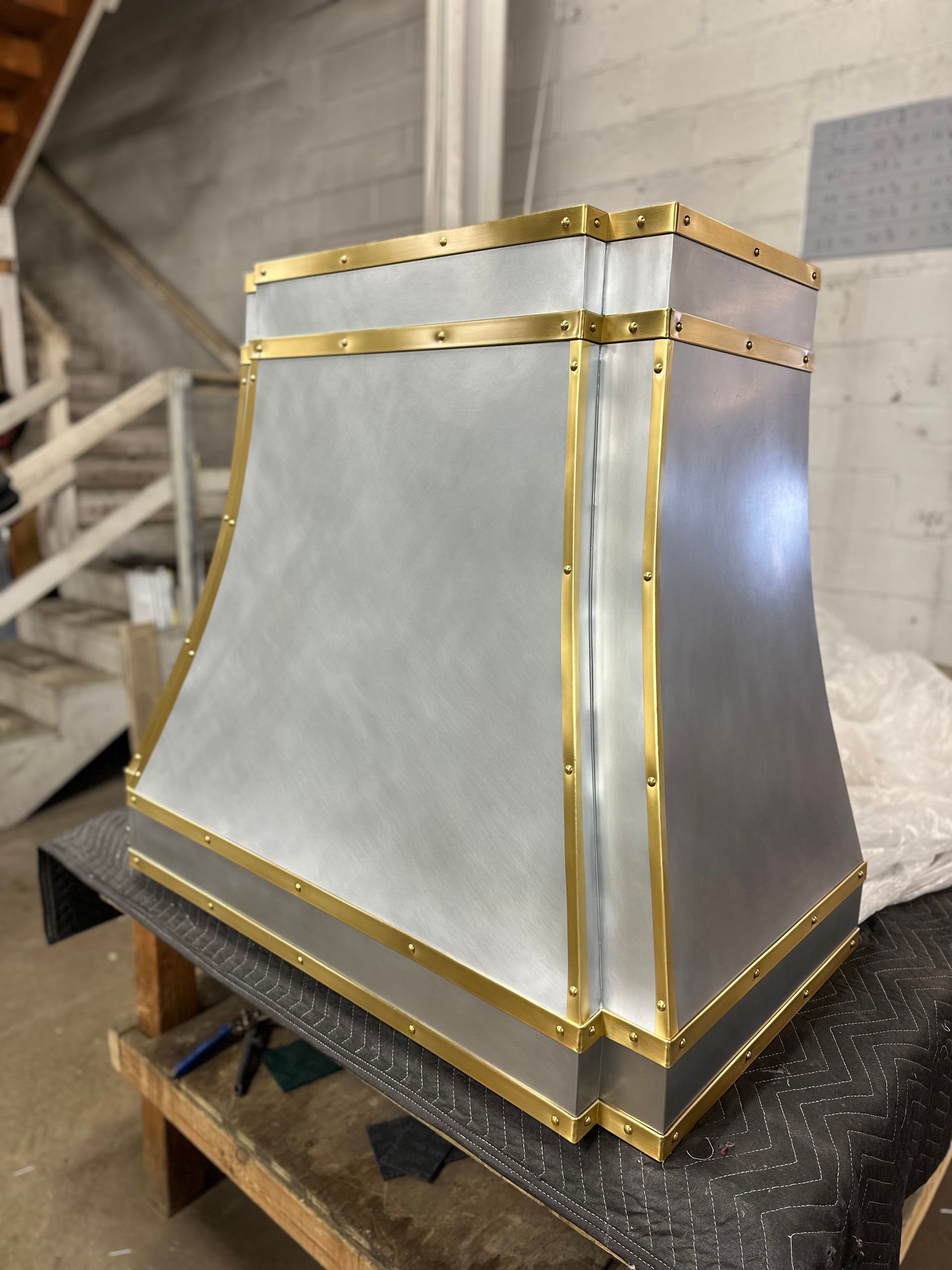 A silver and gold lamp shade is sitting on a wooden table