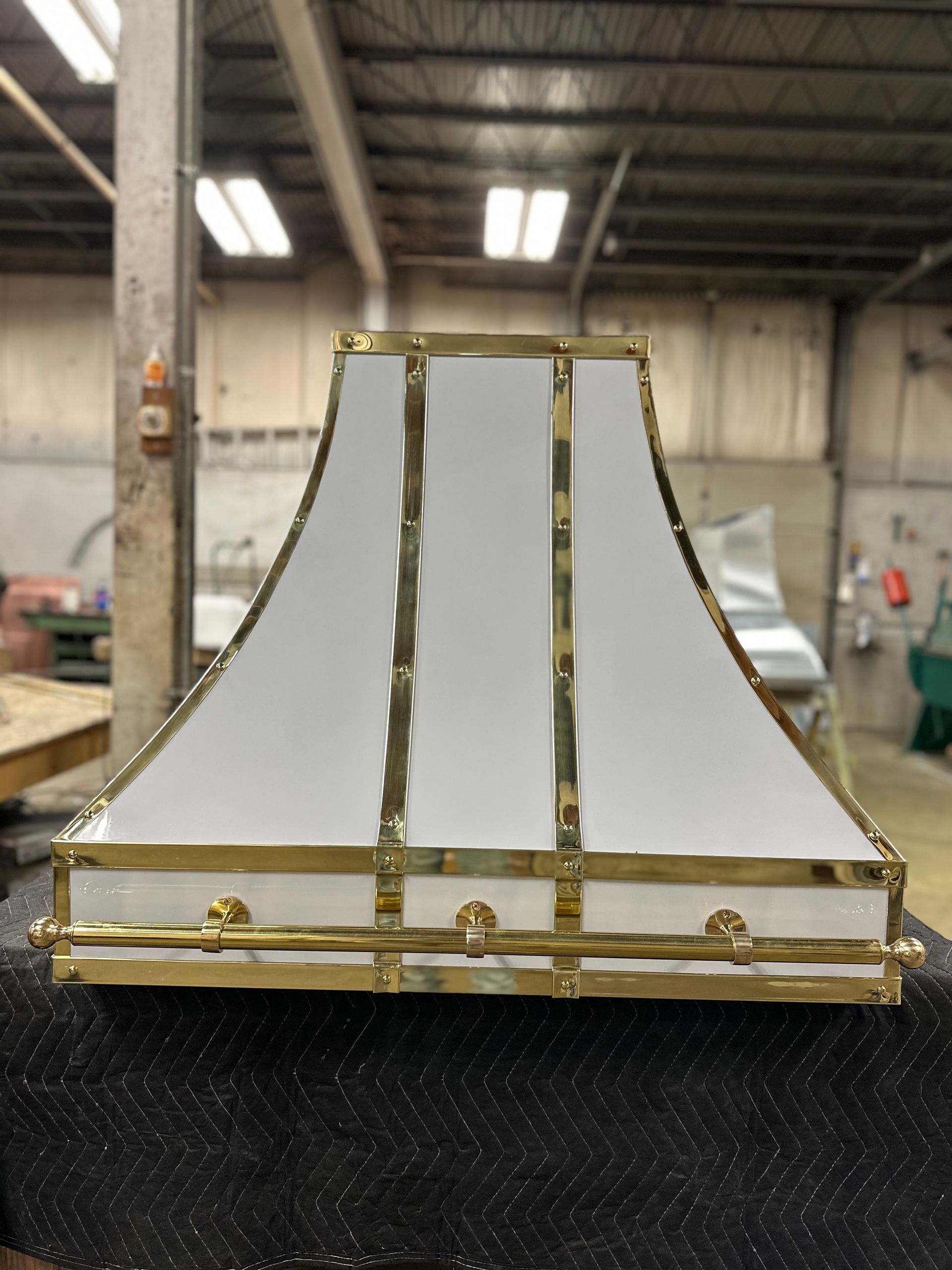 A white and gold lamp shade is sitting on a table in a warehouse