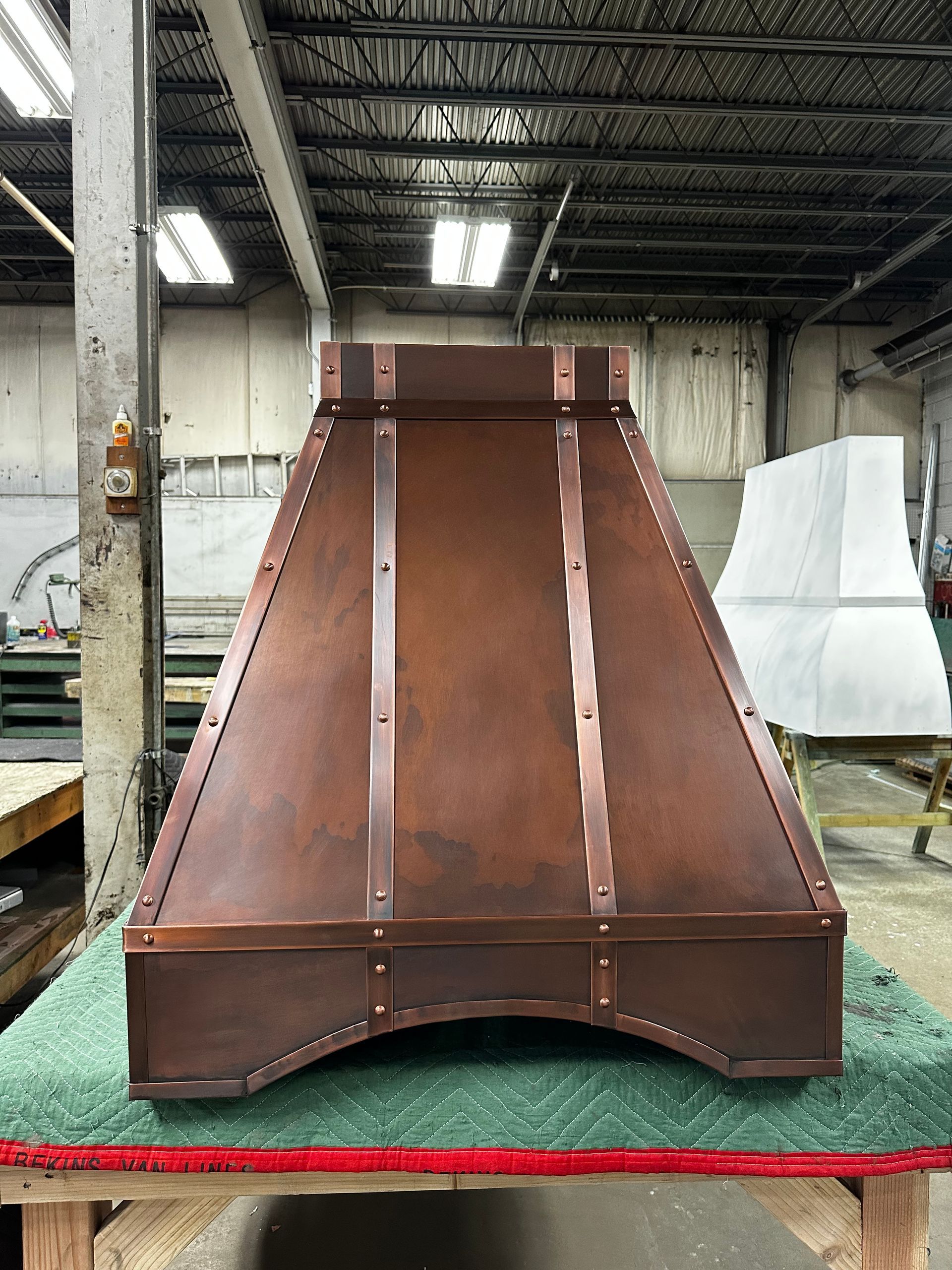 A copper hood is sitting on a table in a warehouse.