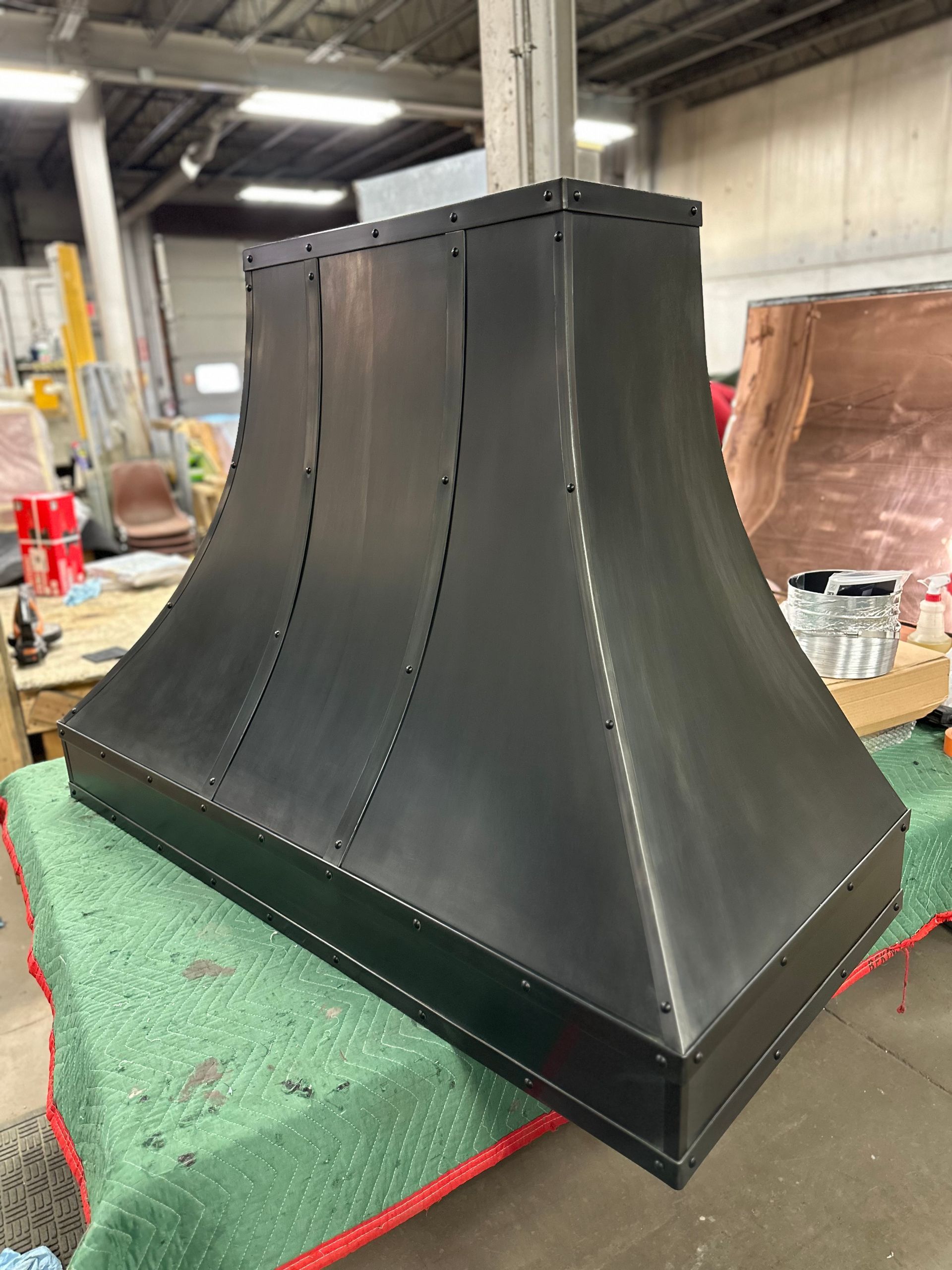 A black hood is sitting on top of a green table in a warehouse.