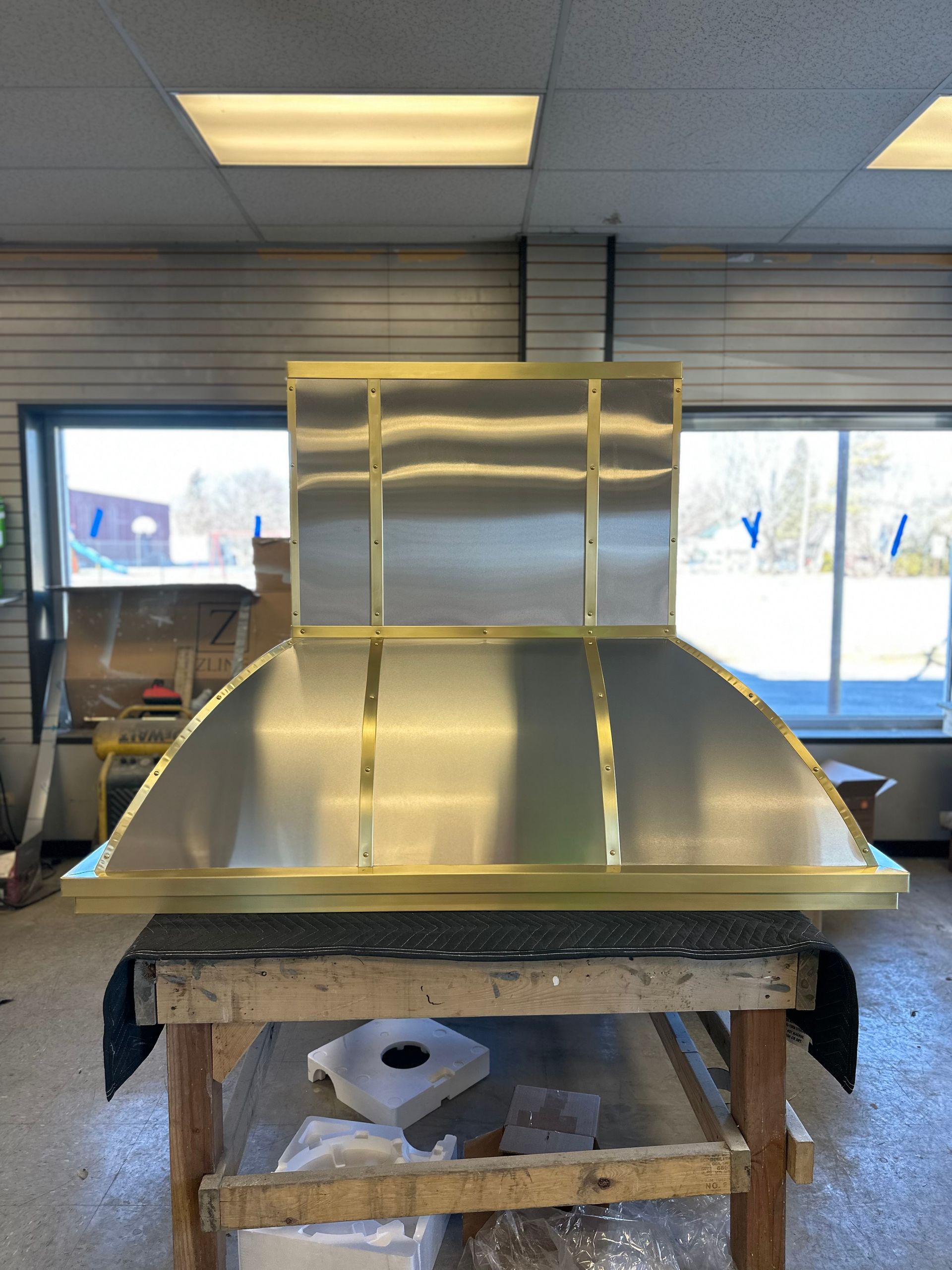 A stainless steel hood is sitting on a wooden table