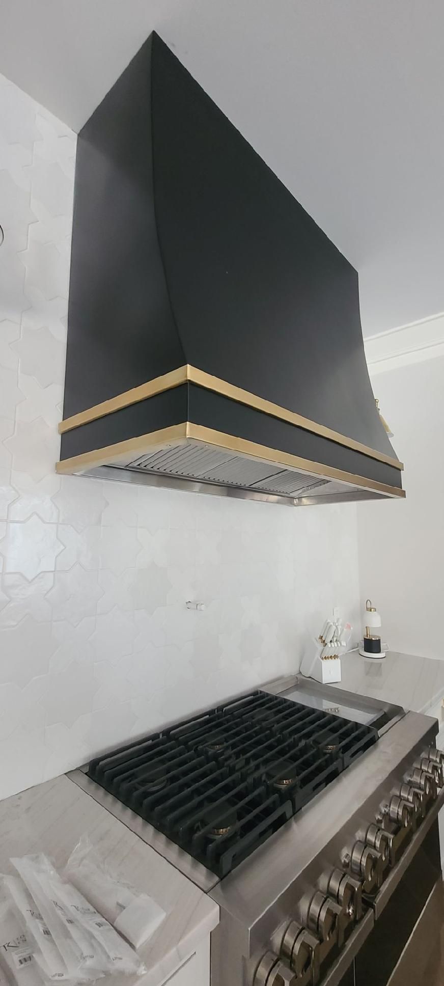 A kitchen with a black stove top oven and a black hood.