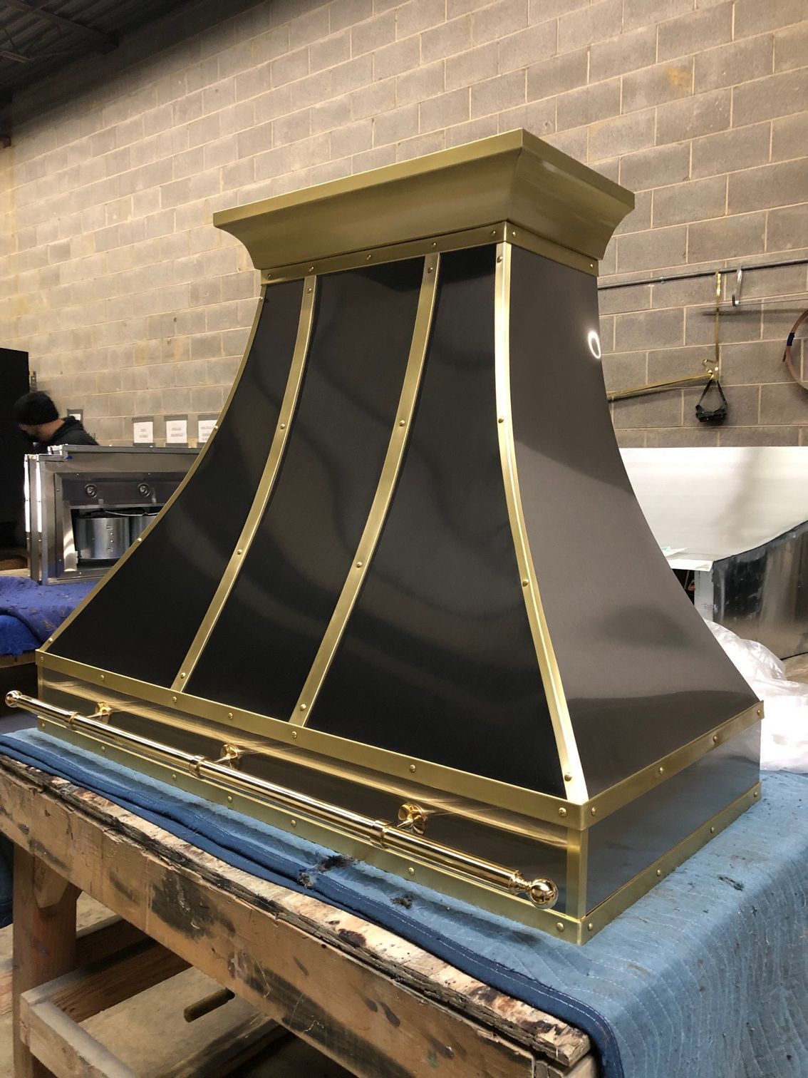 A black and gold hood is sitting on a wooden table.