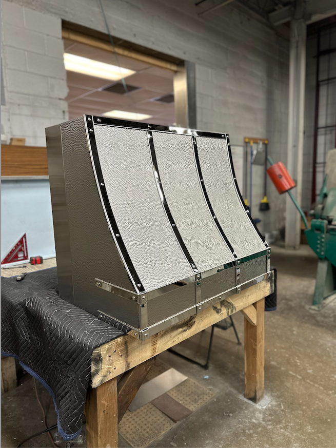 A stainless steel box is sitting on top of a wooden table.