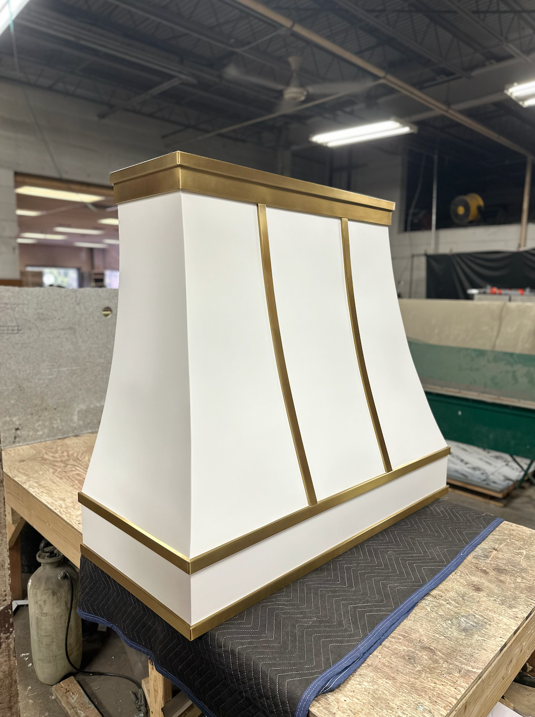 A white lampshade with brass trim is sitting on a wooden table.